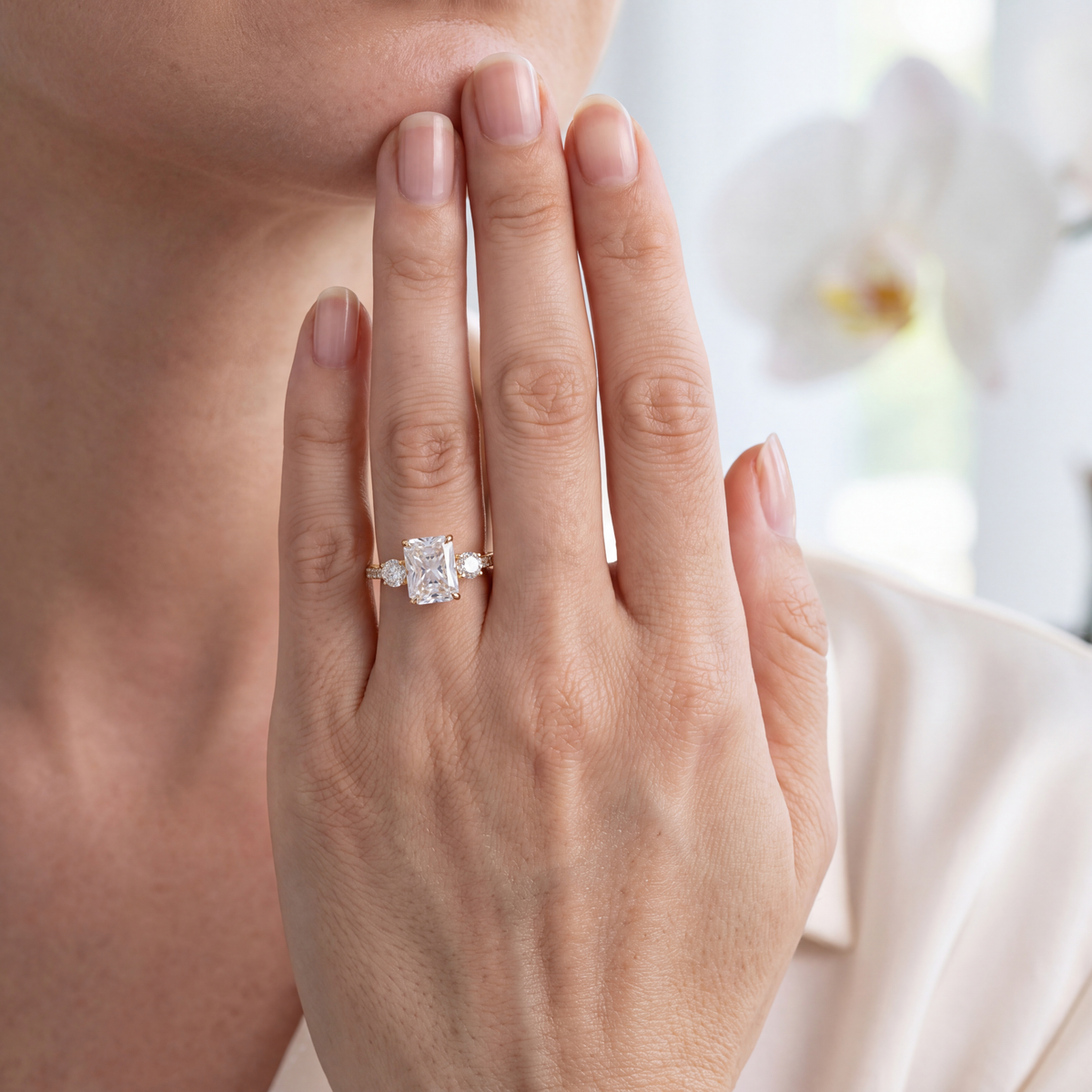 Yellow gold radiant cut moissanite three-stone engagement ring worn on a hand.