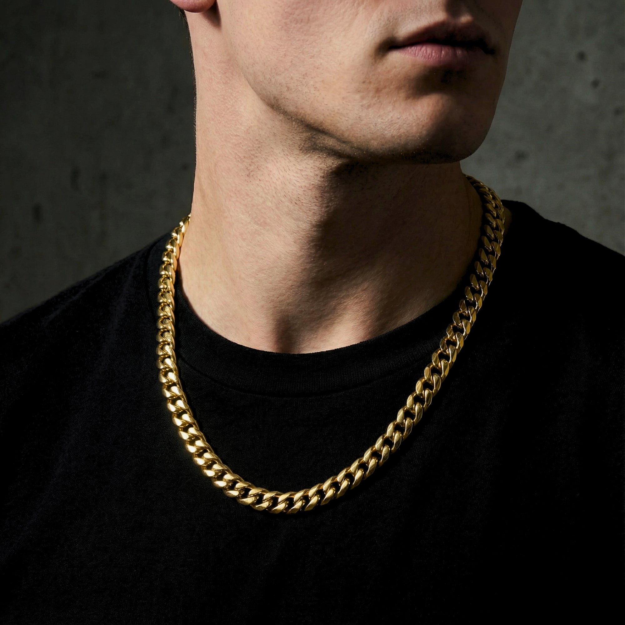 Model wearing the 8mm gold Cuban link chain necklace in stainless steel over a black t-shirt.