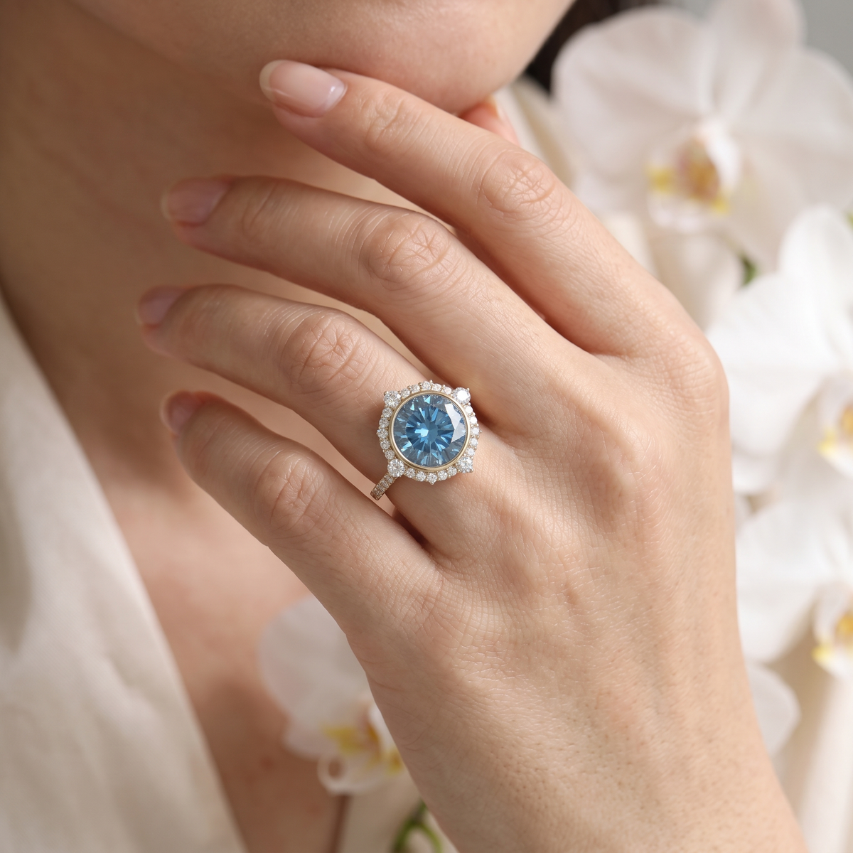 Model wearing a round blue moissanite halo engagement ring in rose gold.