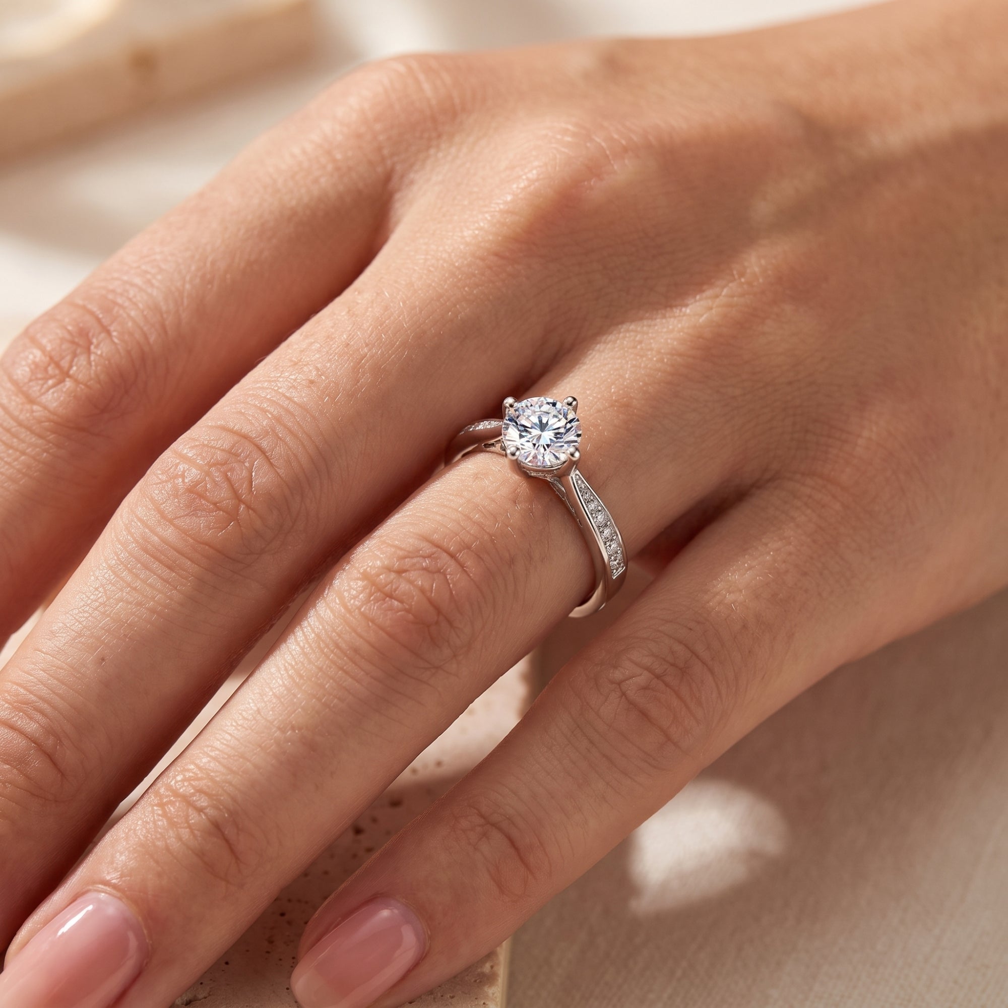 Sterling silver round cut solitaire promise ring with micro-pavé accents worn on a woman's ring finger.