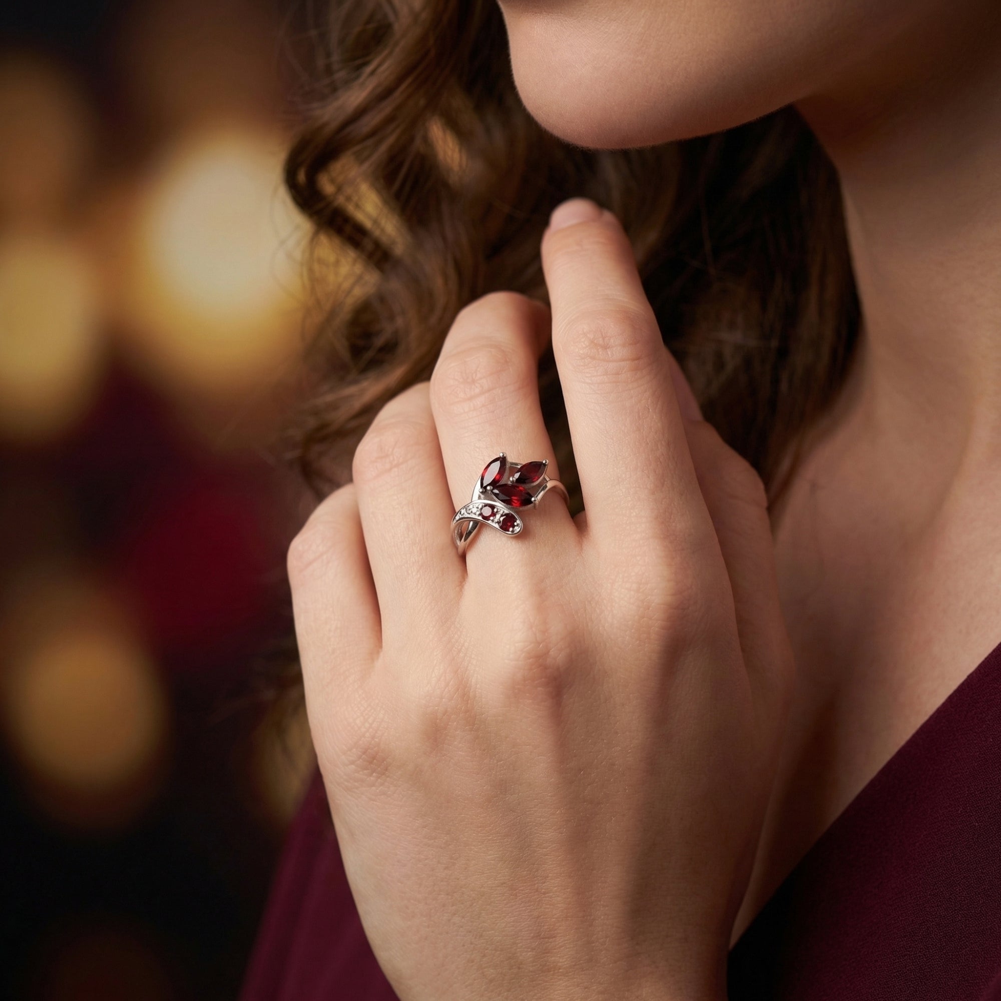 Woman wearing the Elestria sterling silver garnet cluster ring on her finger, showing its botanical bypass design.