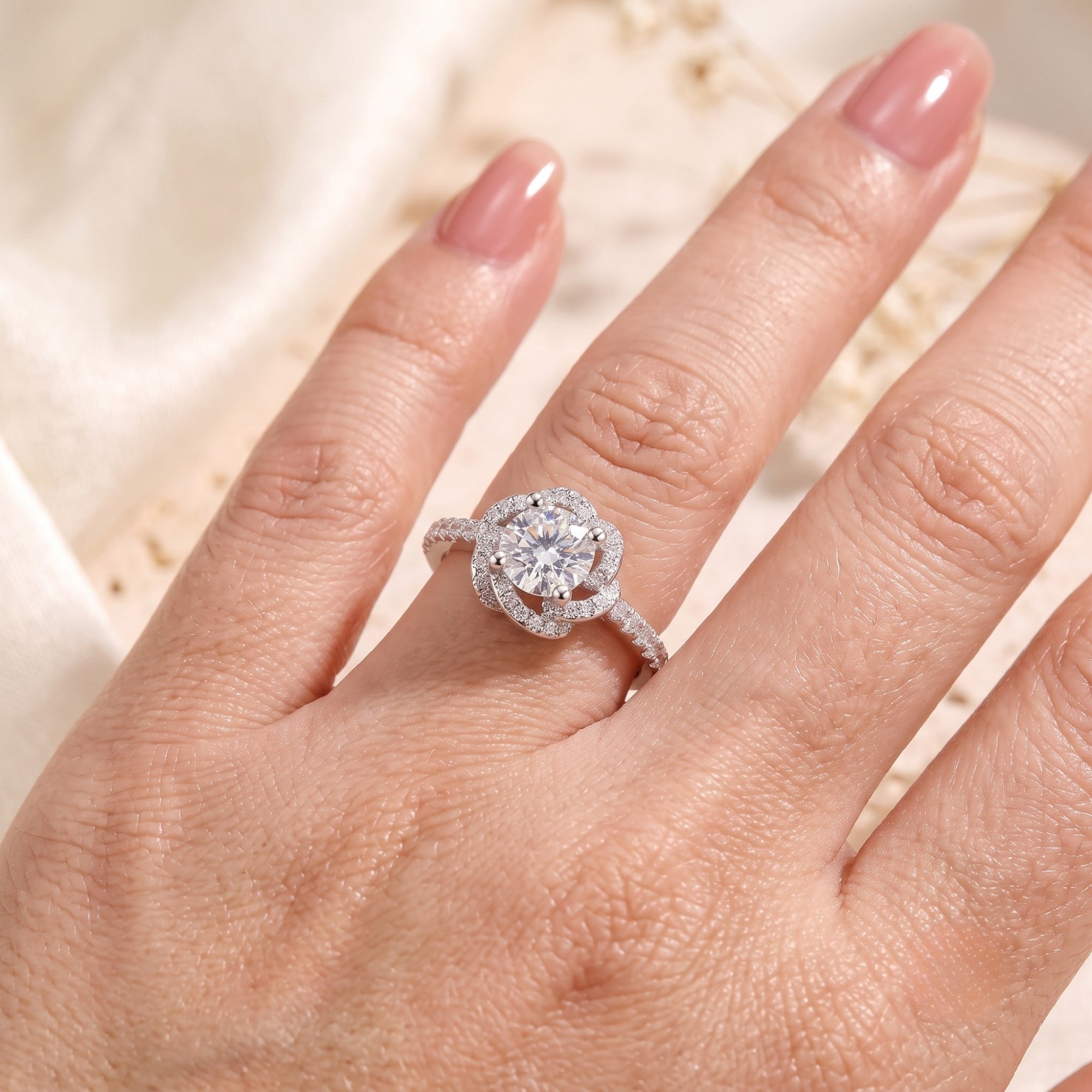 Sterling silver rosette swirl halo ring with round simulated diamond worn on a woman's finger.