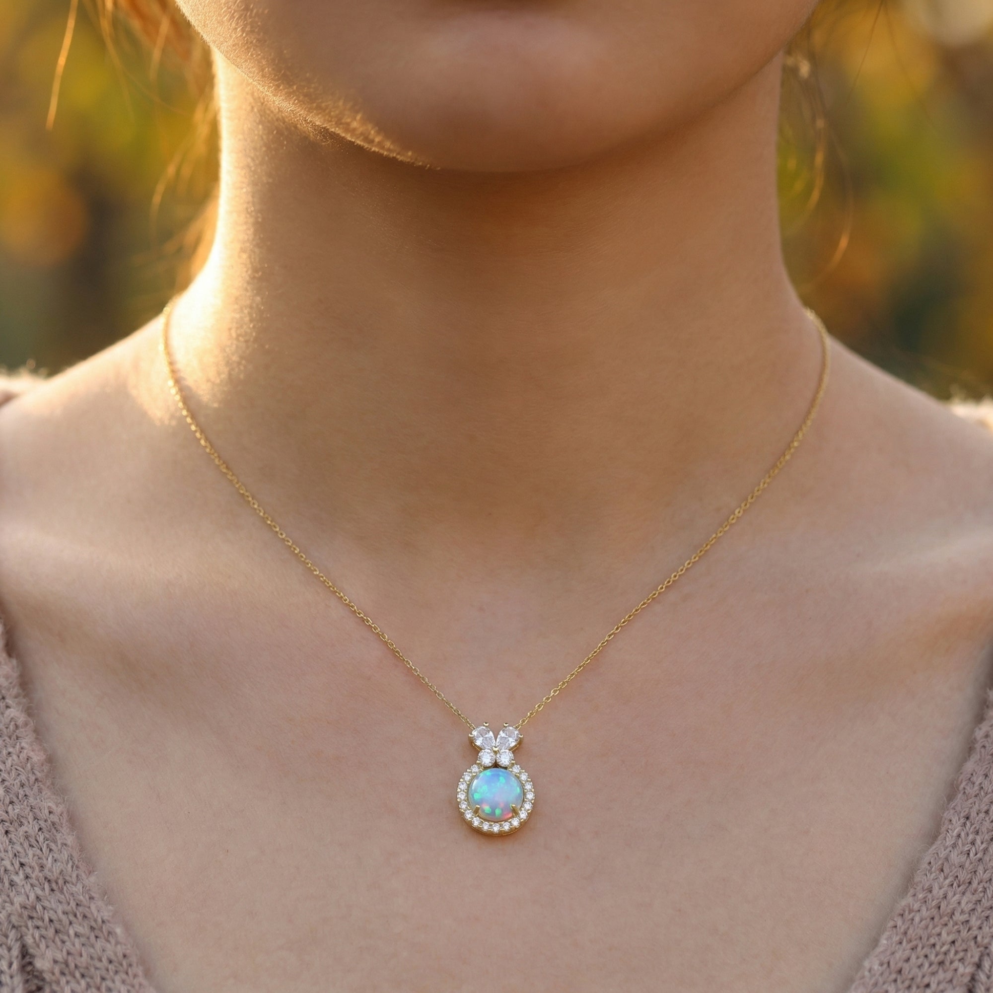 Model wearing the gold vermeil Orianne necklace featuring a round blue opal pendant with a crystal halo.