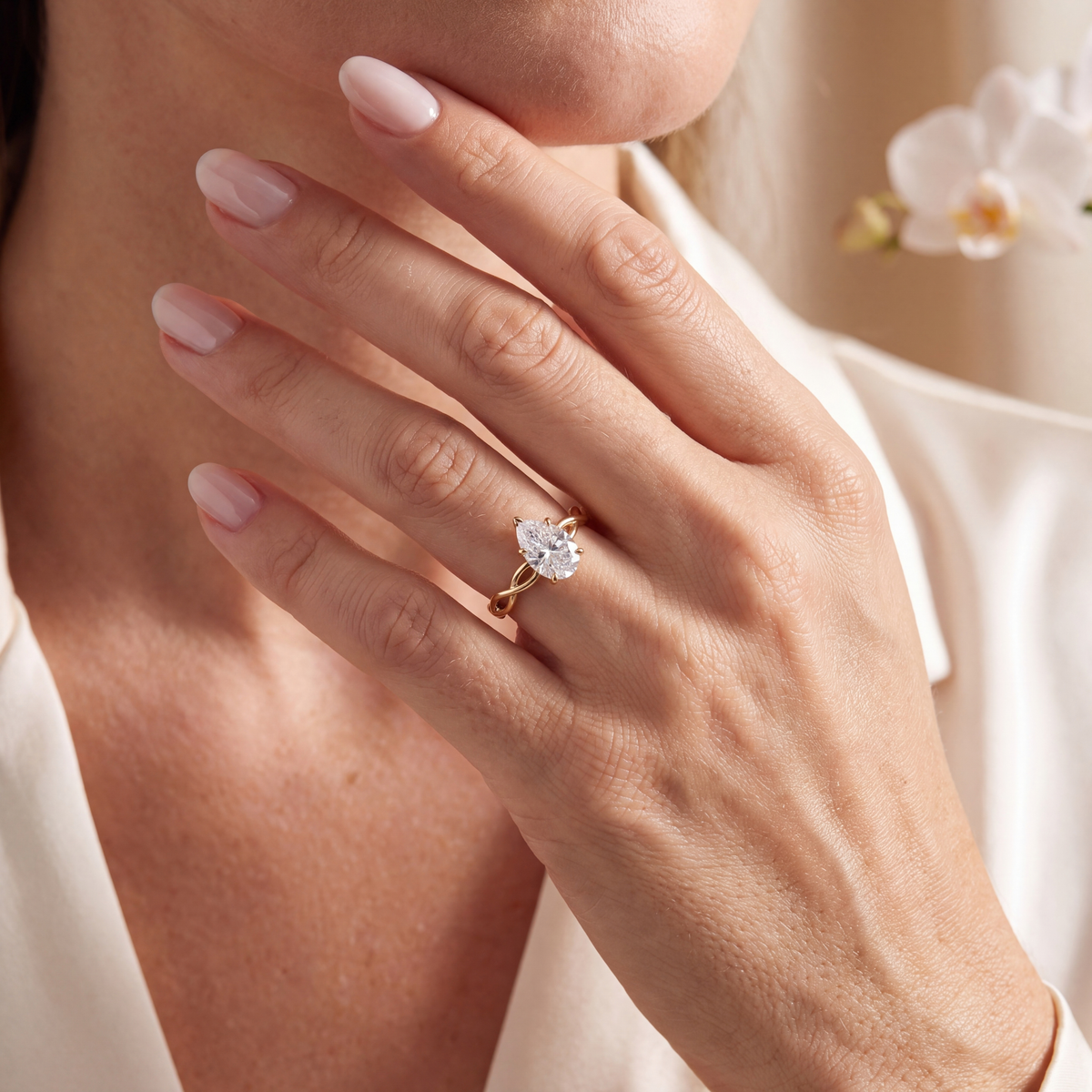 A woman wearing a yellow gold pear-cut moissanite ring with a twisted band setting.