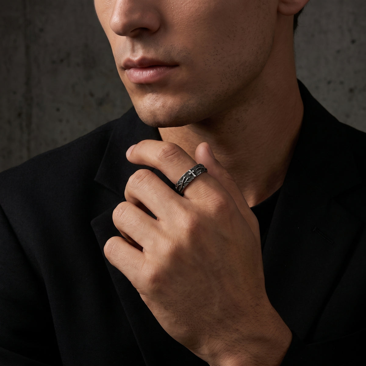 Man wearing the silver cross ring on his index finger while adjusting a black blazer