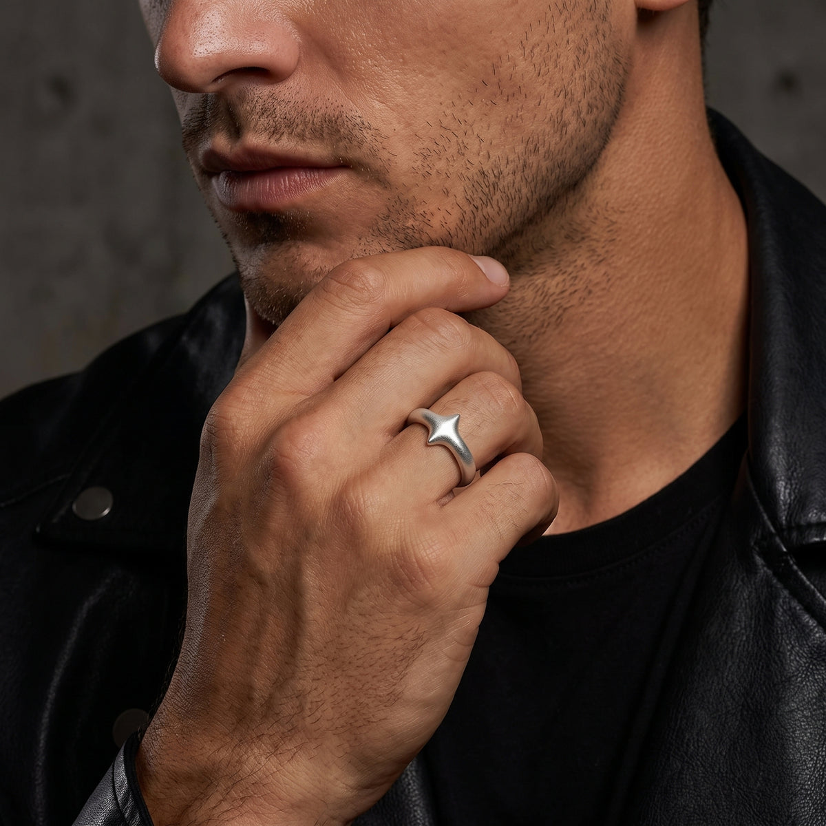 Man wearing the matte silver starburst ring on his ring finger while resting his hand near his chin.