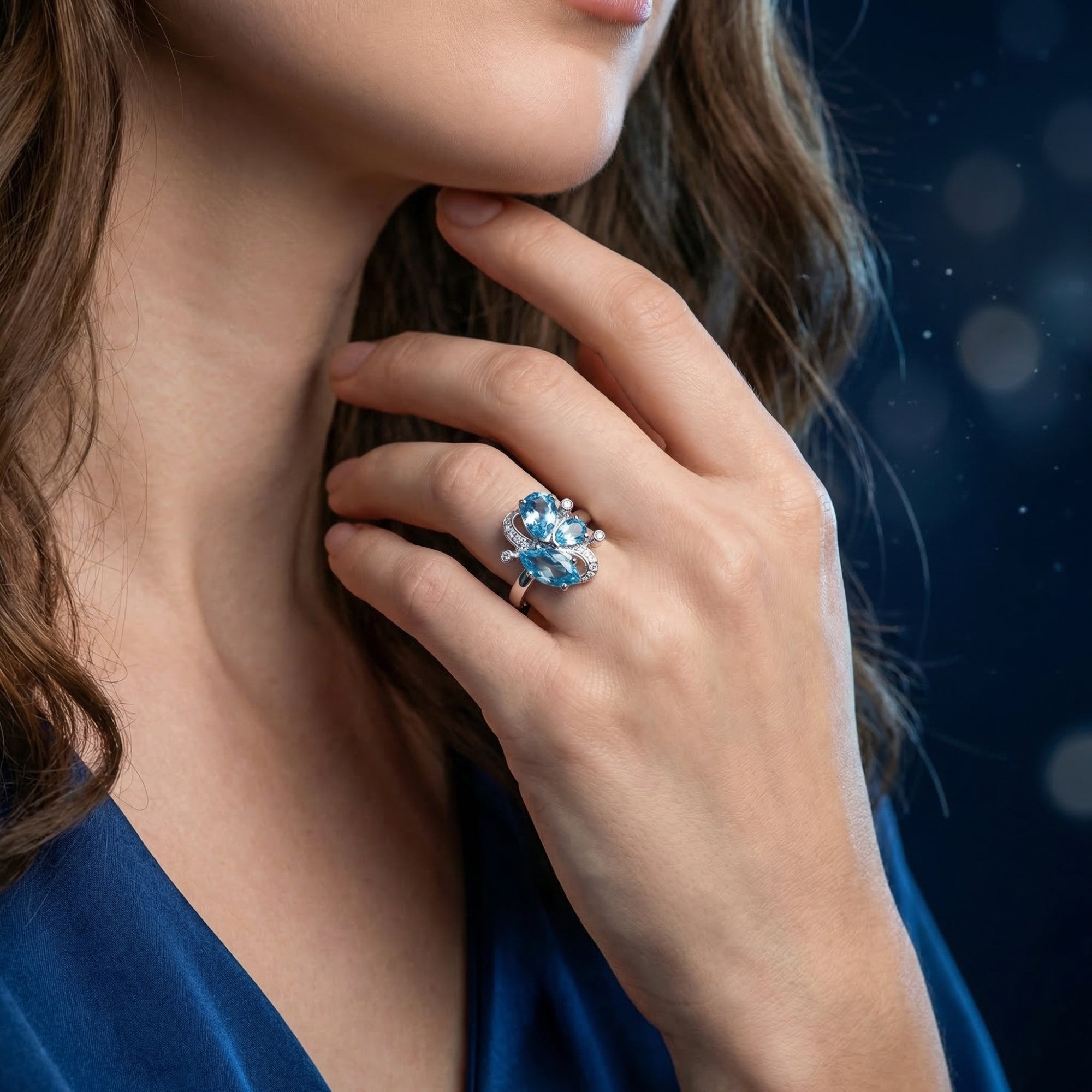 Model wearing the silver Mariposa ring with blue topaz stones, showing the jewelry's scale on a hand.
