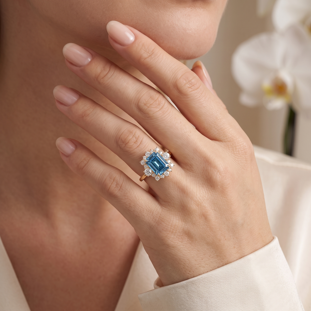A woman wearing an emerald-cut blue moissanite halo ring in rose gold.