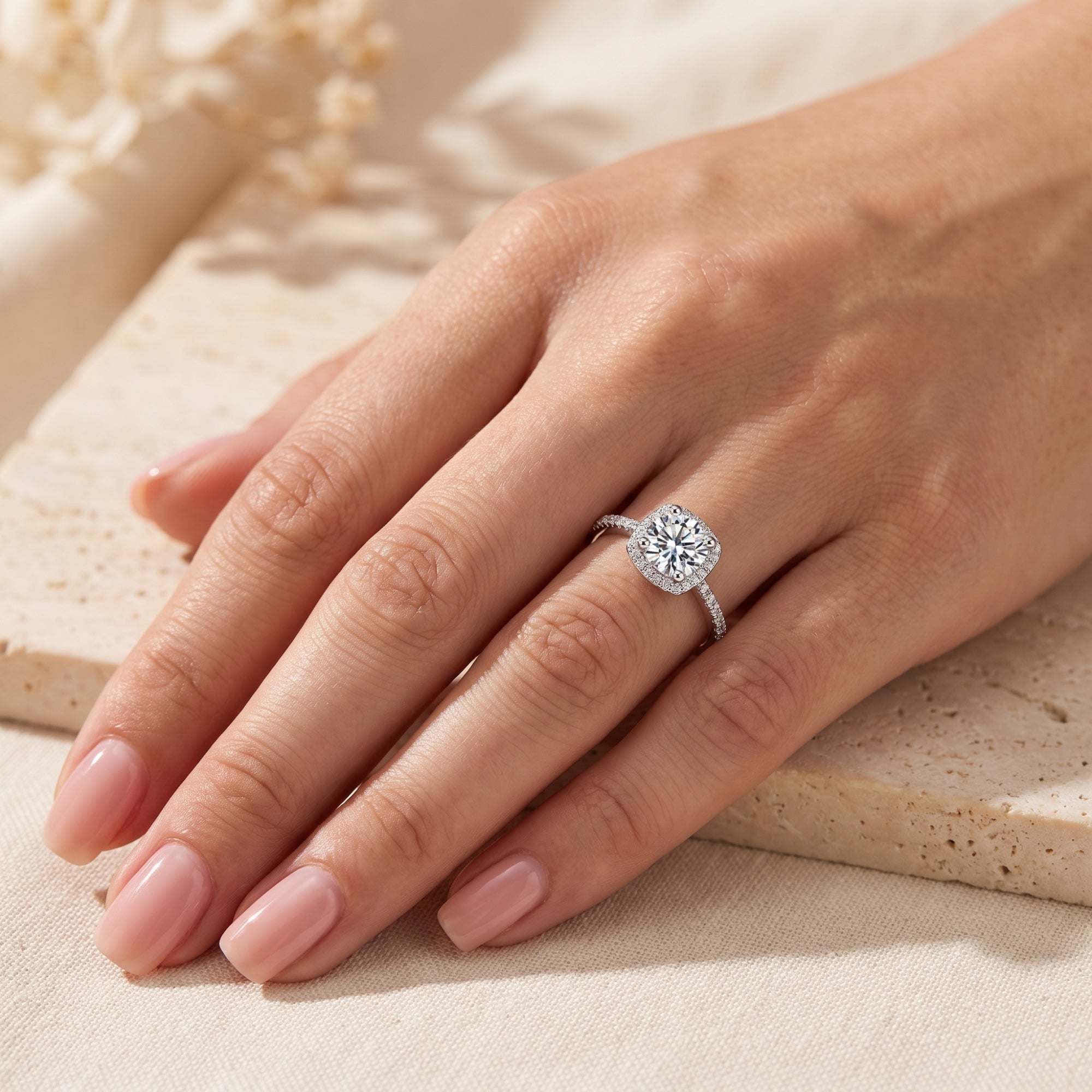 Sterling silver cushion halo ring with brilliant-cut cubic zirconia worn on a woman's hand.
