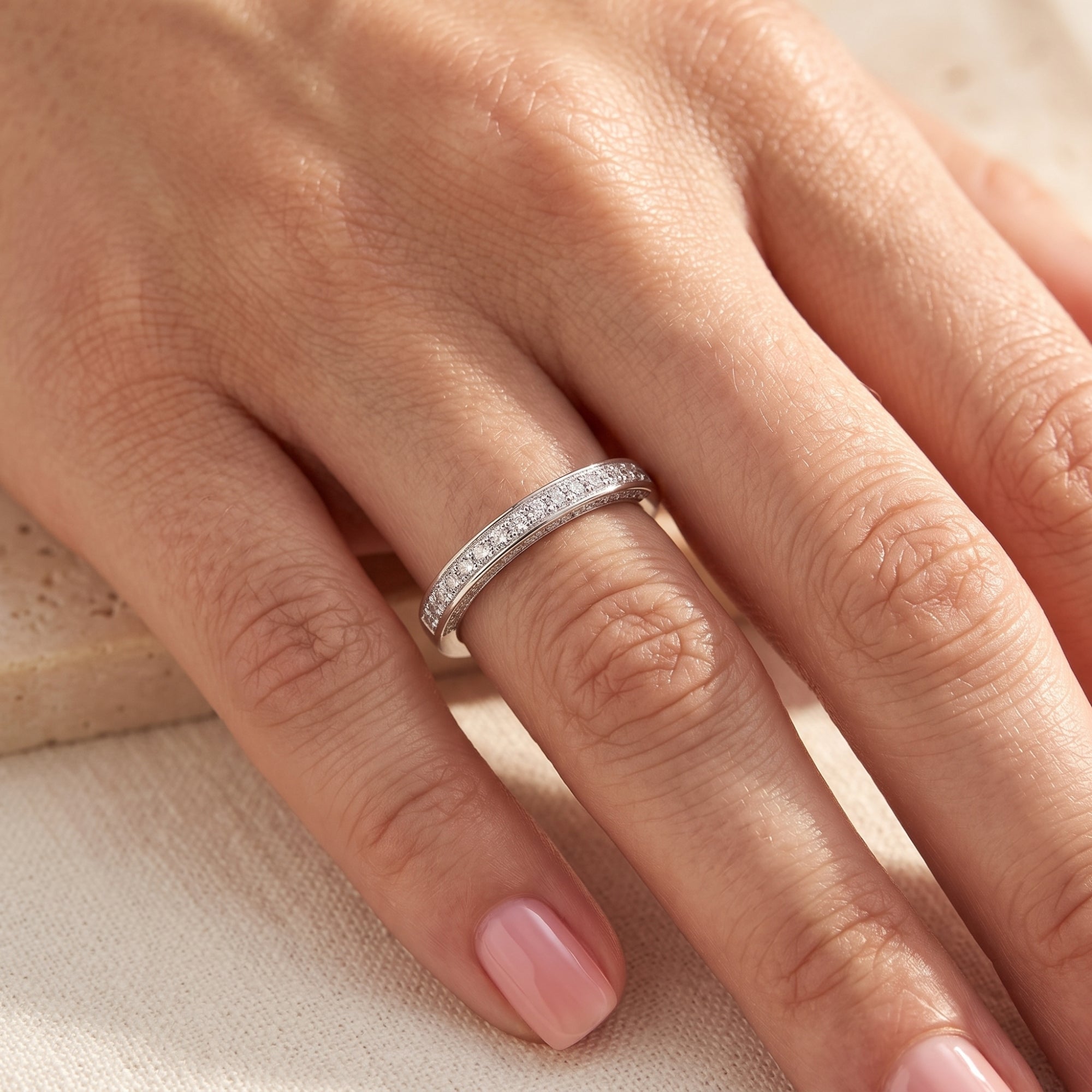 Double row pavé silver promise ring worn on a woman's finger.