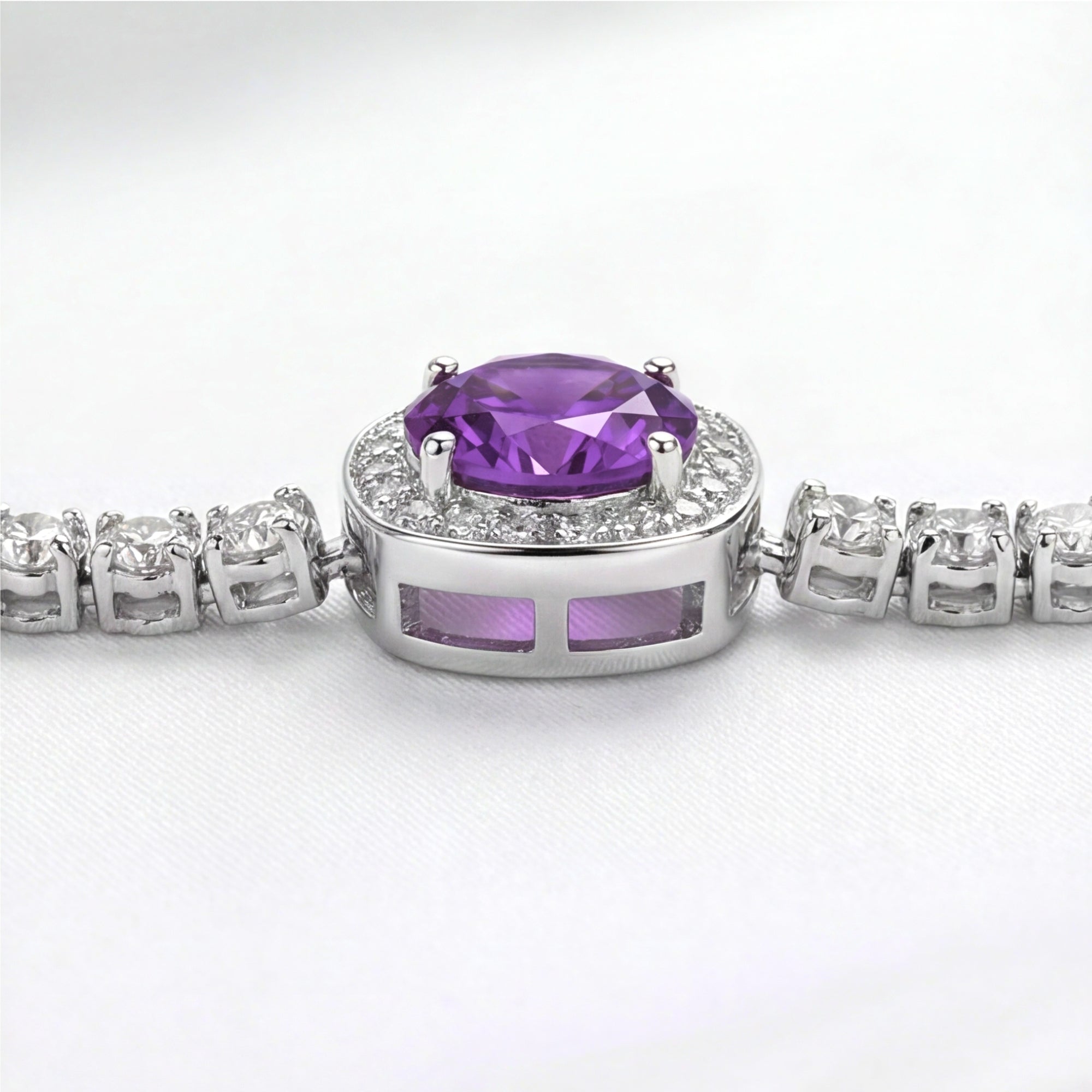 Macro view of a round cut purple simulated amethyst in a sterling silver halo setting with side gallery detail.