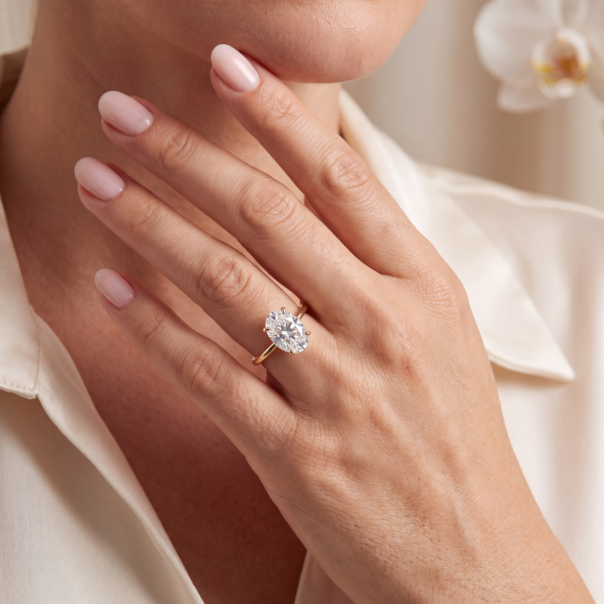 Lifestyle view of a woman wearing an oval moissanite solitaire ring in yellow gold.