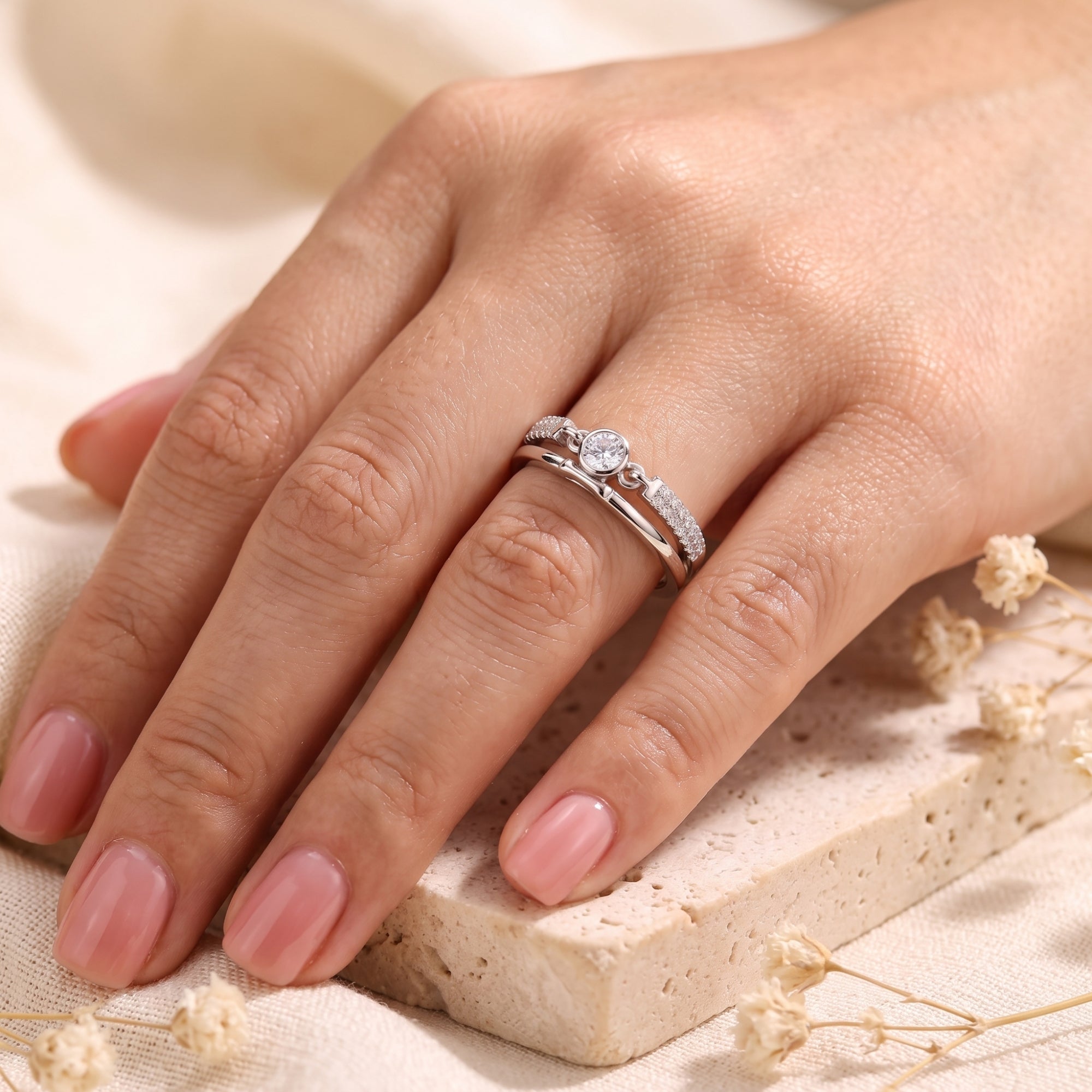 Sterling silver Lyra double band ring with round simulated diamond worn on a model's hand.