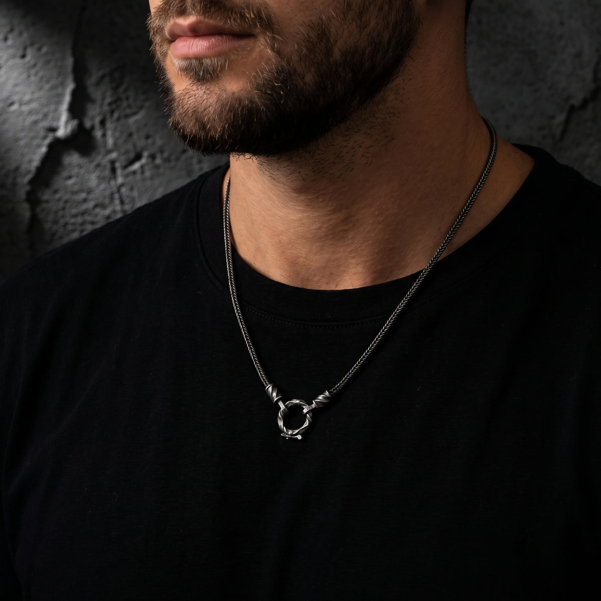 Model wearing the silver twisted ring pendant necklace over a plain black T-shirt.