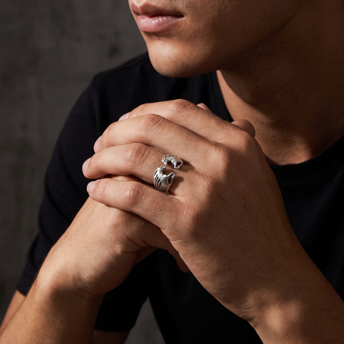 Model wearing the silver dual horse open ring on a finger while clasping both hands near his face.