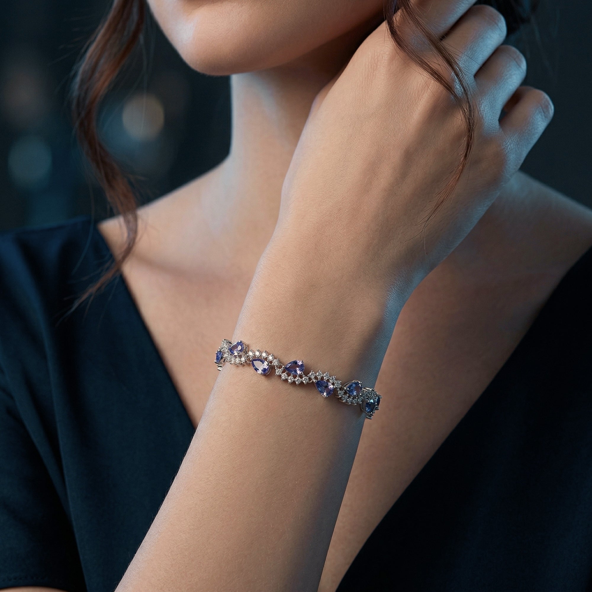A woman wearing the pear cut tanzanite and silver tennis bracelet on her wrist.