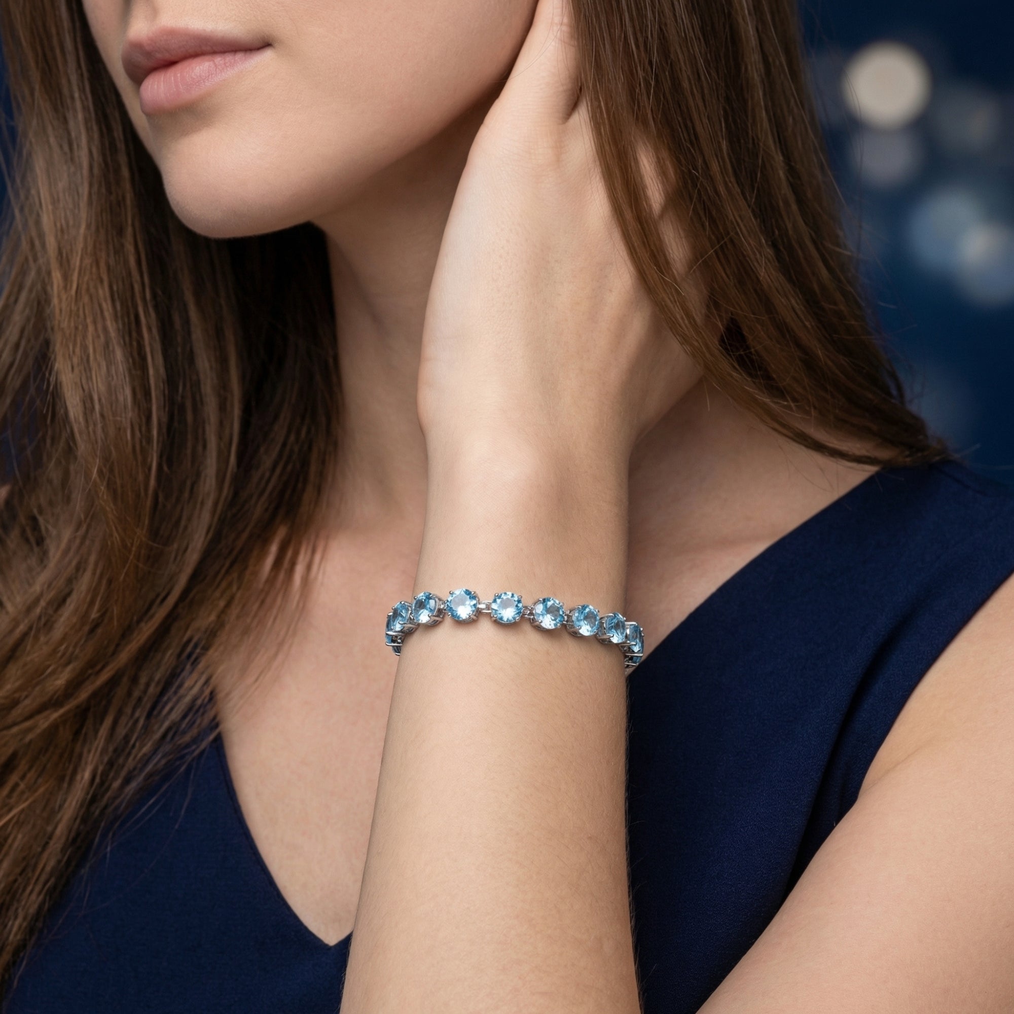 Oceari natural Swiss blue topaz tennis bracelet in white gold worn on a woman's wrist.