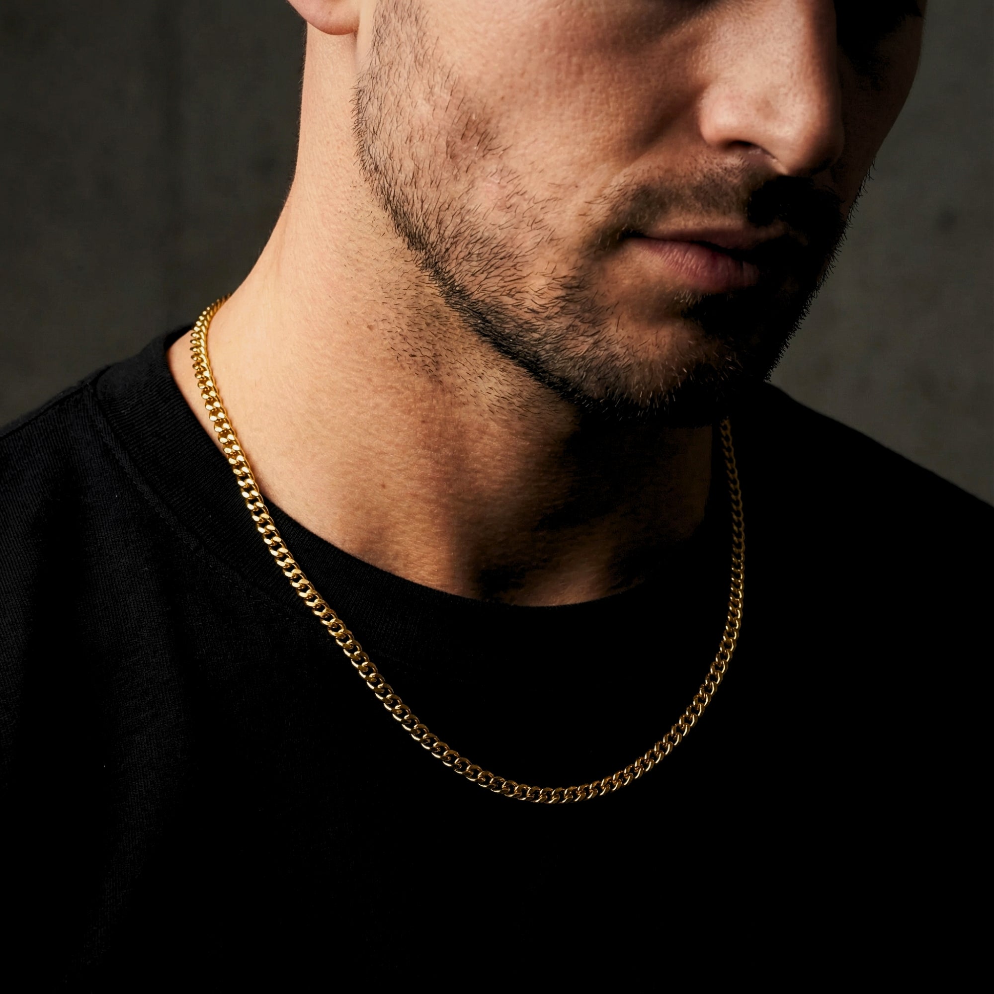Man wearing a 4mm gold stainless steel Miami Cuban link chain over a black crew neck t-shirt.