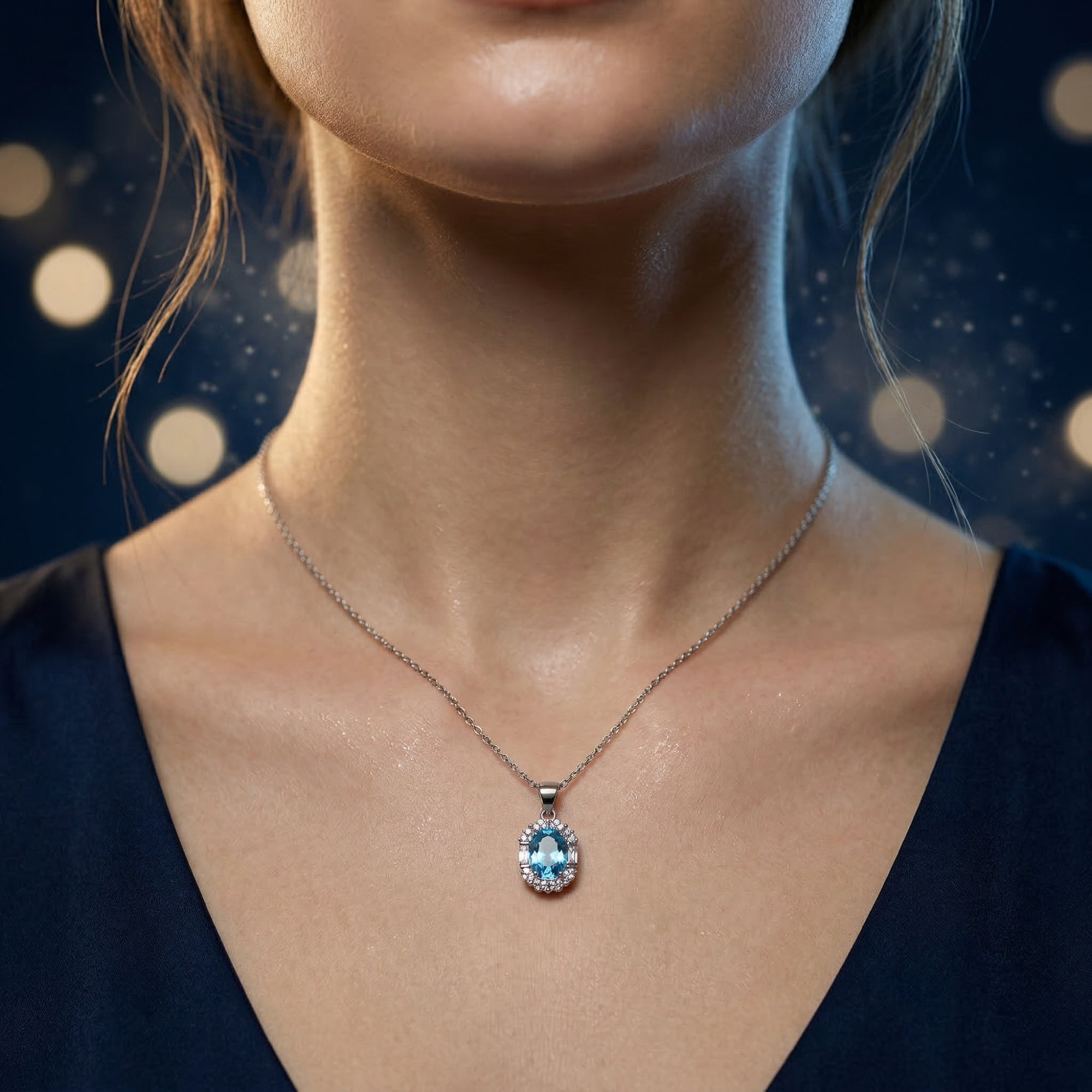 Woman wearing the Thalassene natural blue topaz necklace in white gold against a soft bokeh background.