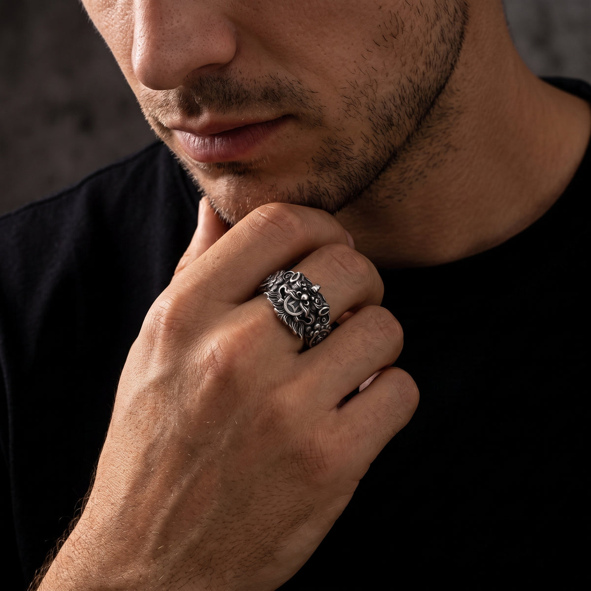Man wearing the oxidized silver Pixiu ring on his finger while holding his hand near his chin.
