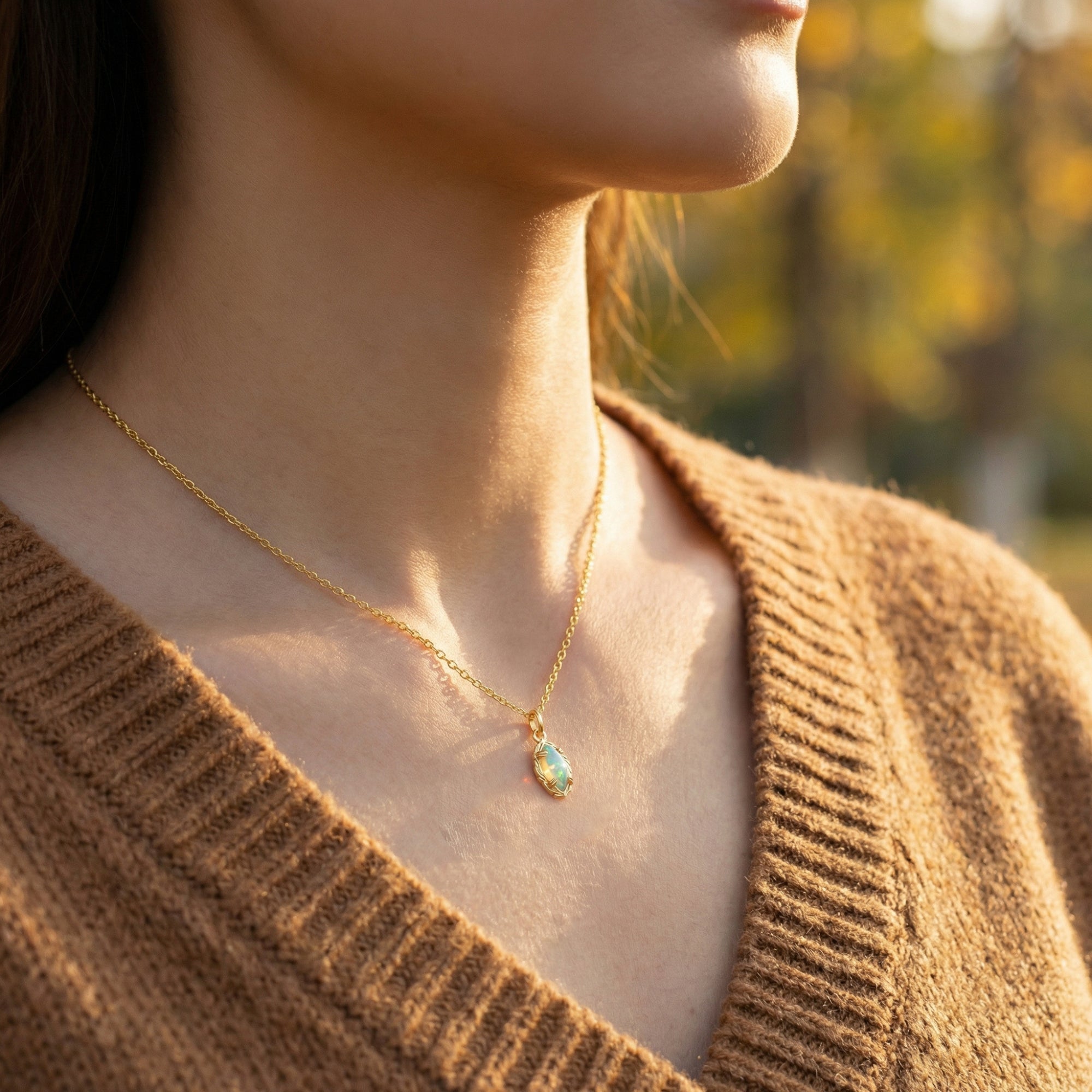 Model wearing the gold marquise-cut white opal necklace outdoors in natural sunlight.