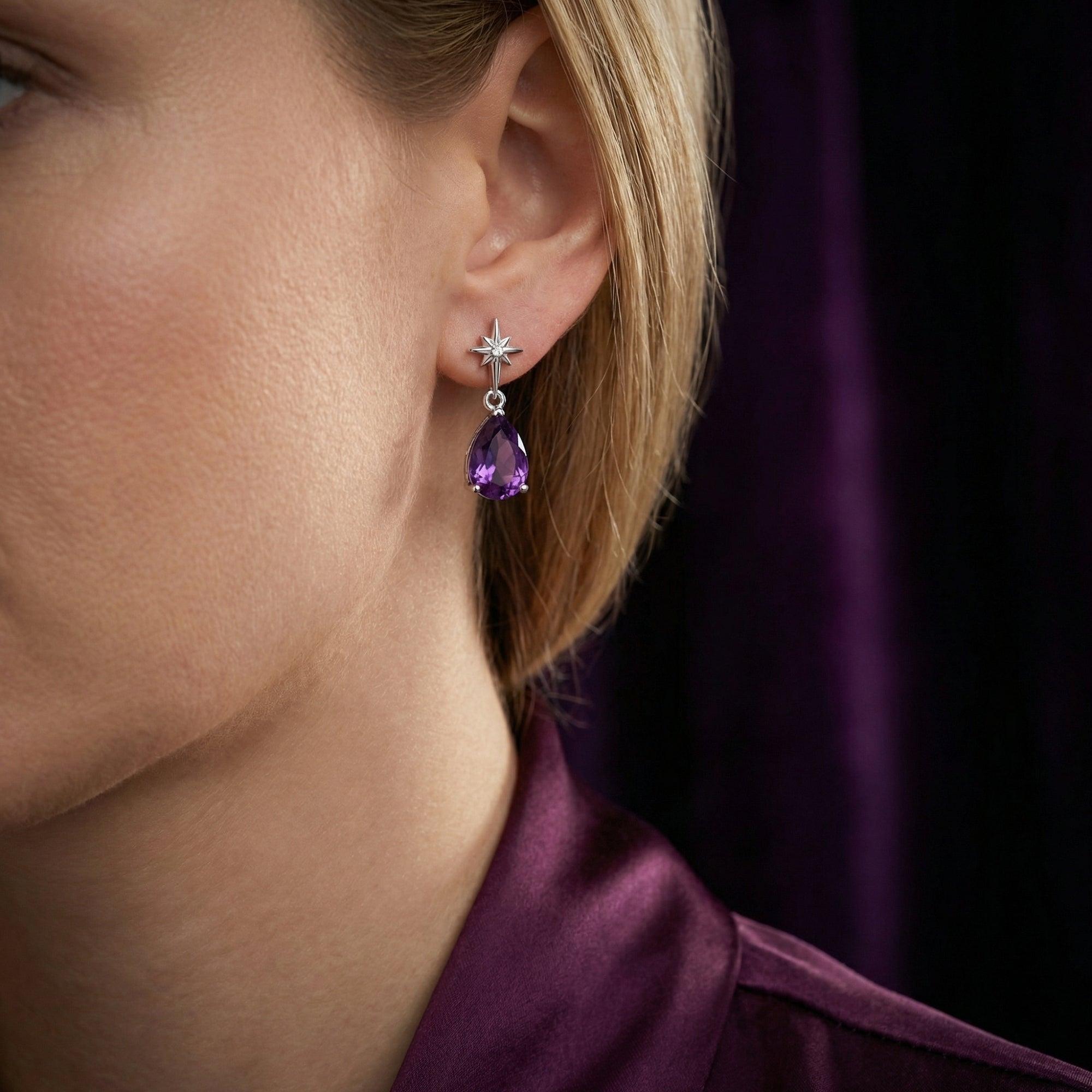 Model wearing a pear cut amethyst drop earring with a sterling silver star stud.