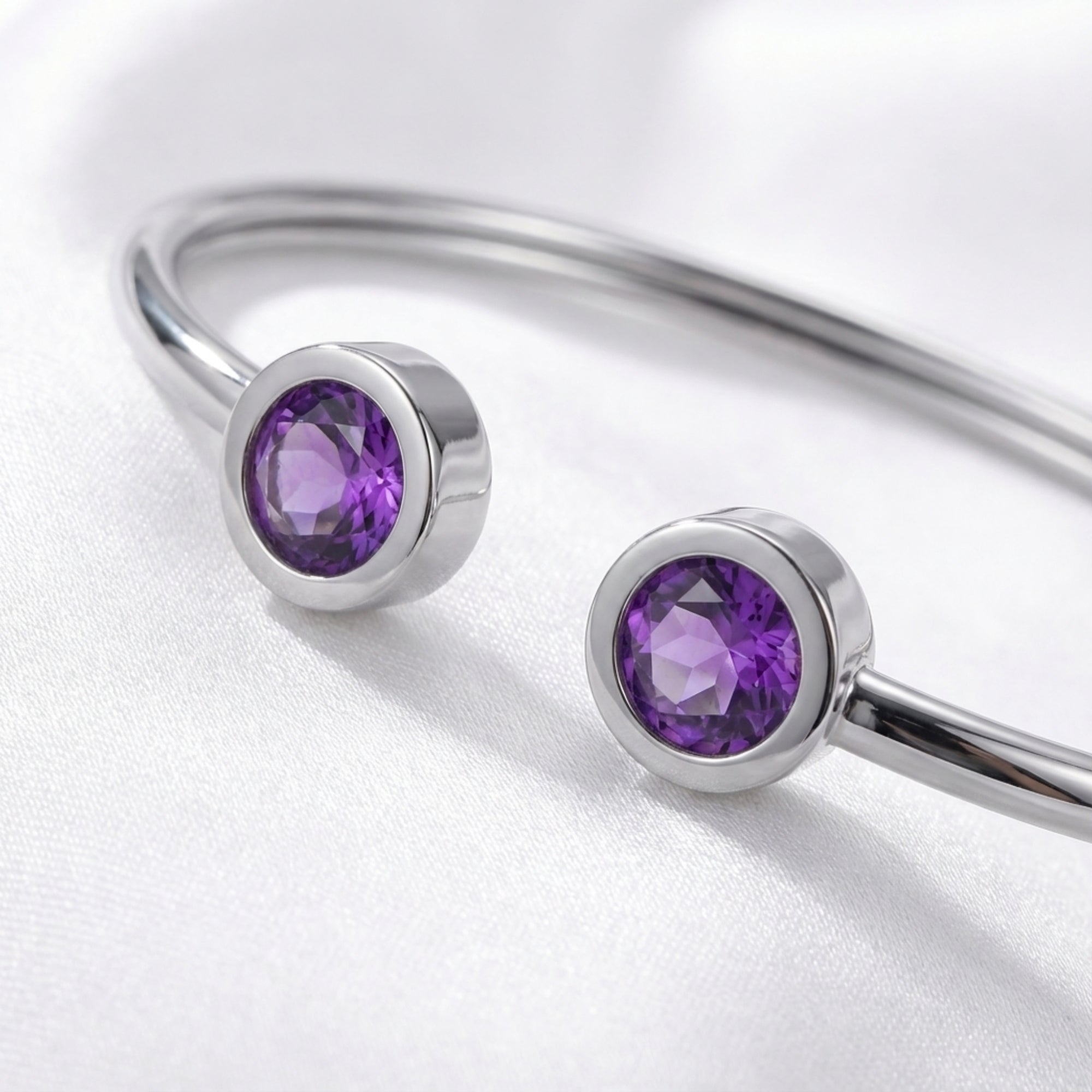 Close-up of round-cut simulated amethyst stones in silver bezel settings on the Liora bypass bracelet.