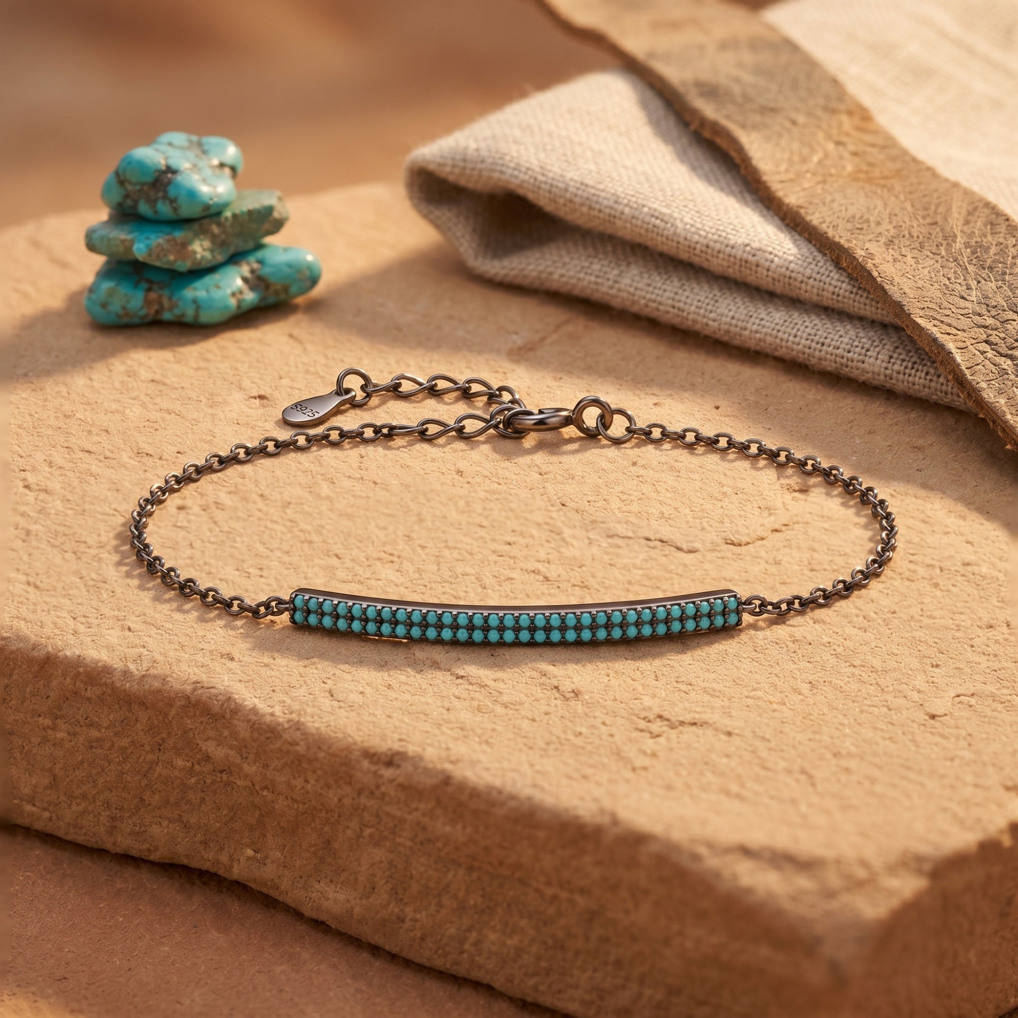 Sterling silver turquoise bar bracelet displayed on a stone slab with raw turquoise stones and fabric accents.