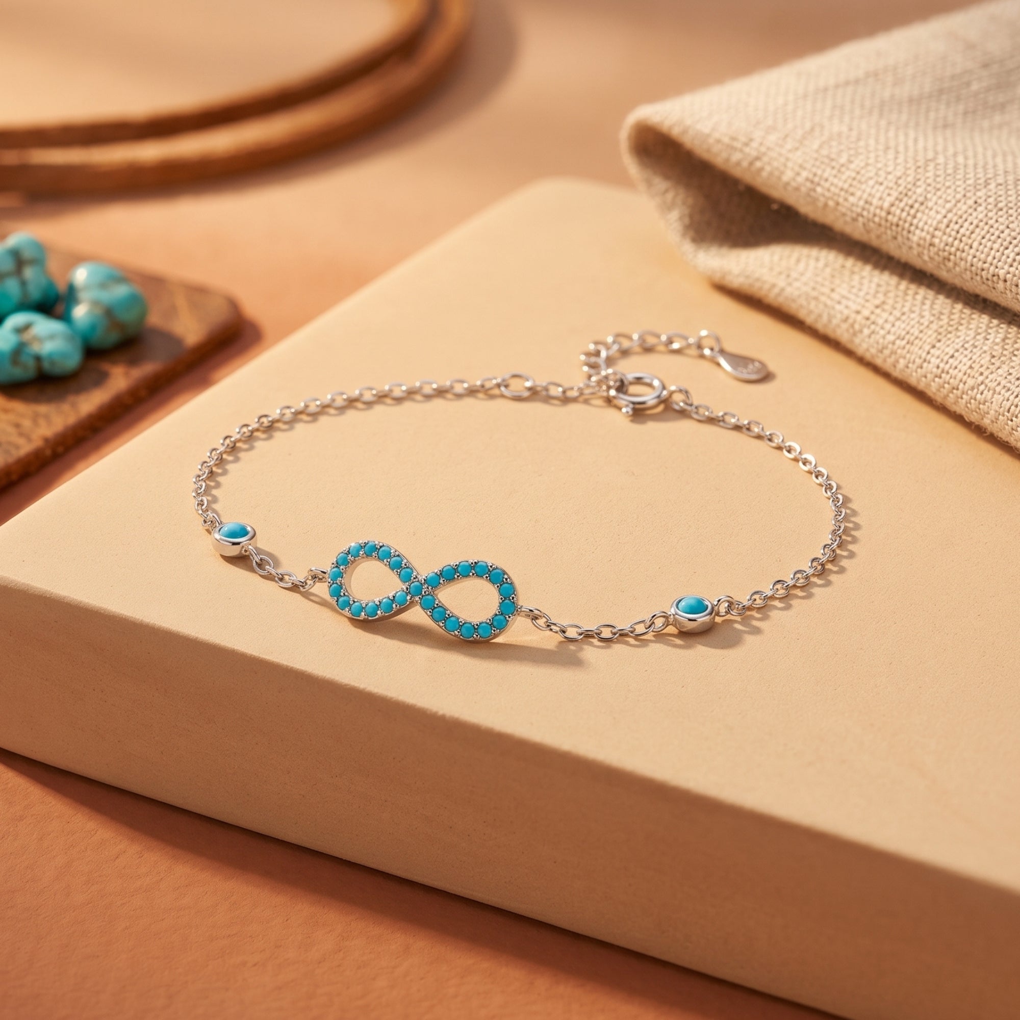 High-polish silver bracelet featuring a turquoise-paved infinity symbol on a neutral display.