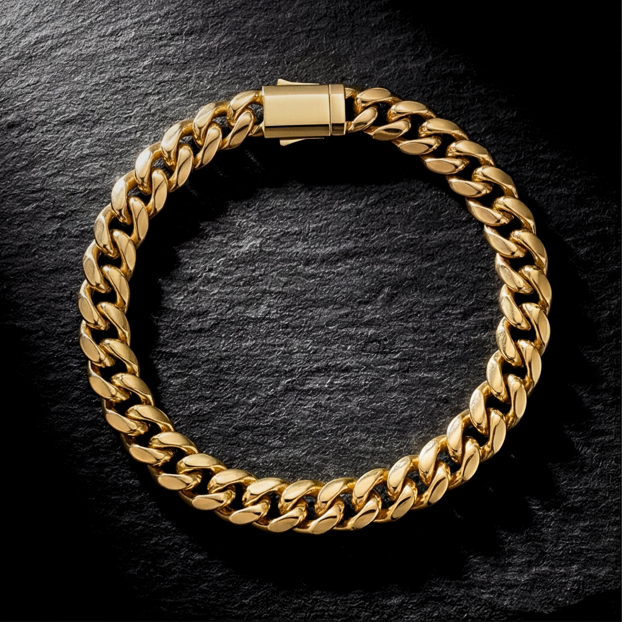 Top-down view of the 8mm gold stainless steel Cuban link bracelet on a dark stone background.