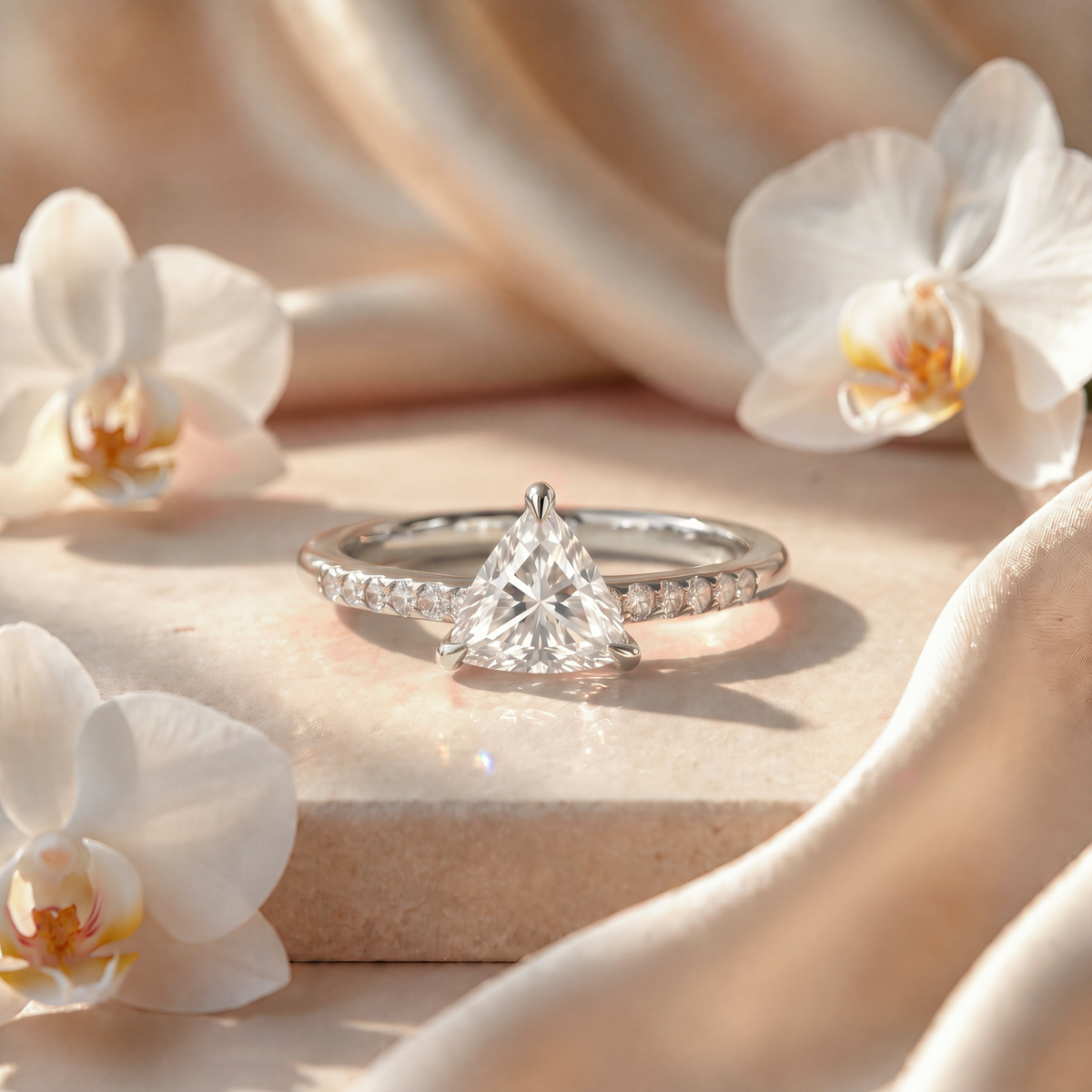 Frontal view of a white gold trillion-cut moissanite engagement ring with a pave band.