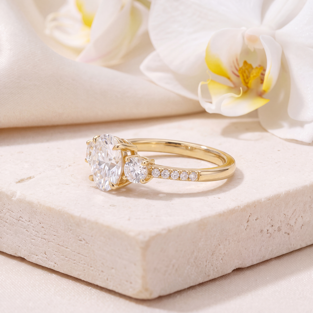 Side view of a yellow gold three-stone oval moissanite ring showcasing the setting details.