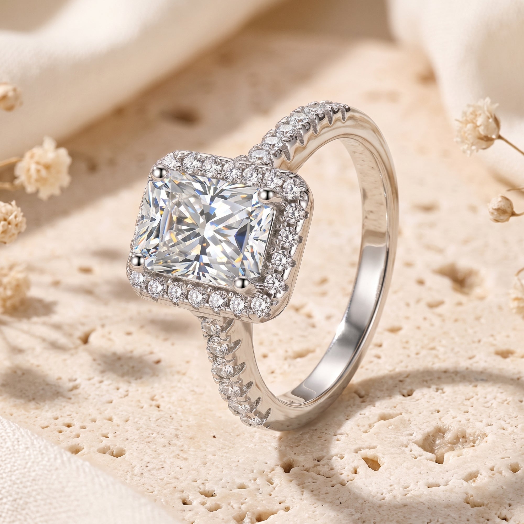 Side profile of a radiant-cut cubic zirconia halo ring in sterling silver on a textured lifestyle background.