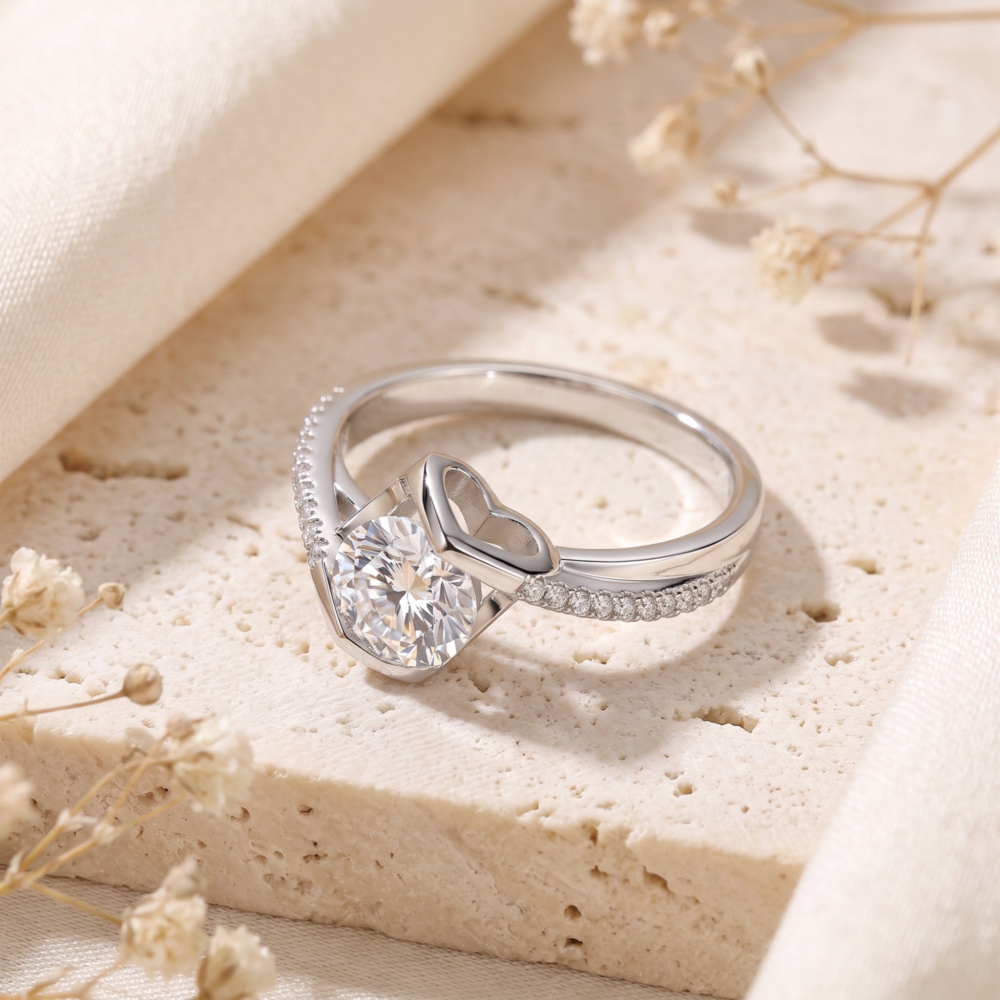 Side view of the silver solitaire ring showing the round-cut stone and secret heart motif in the bypass setting.