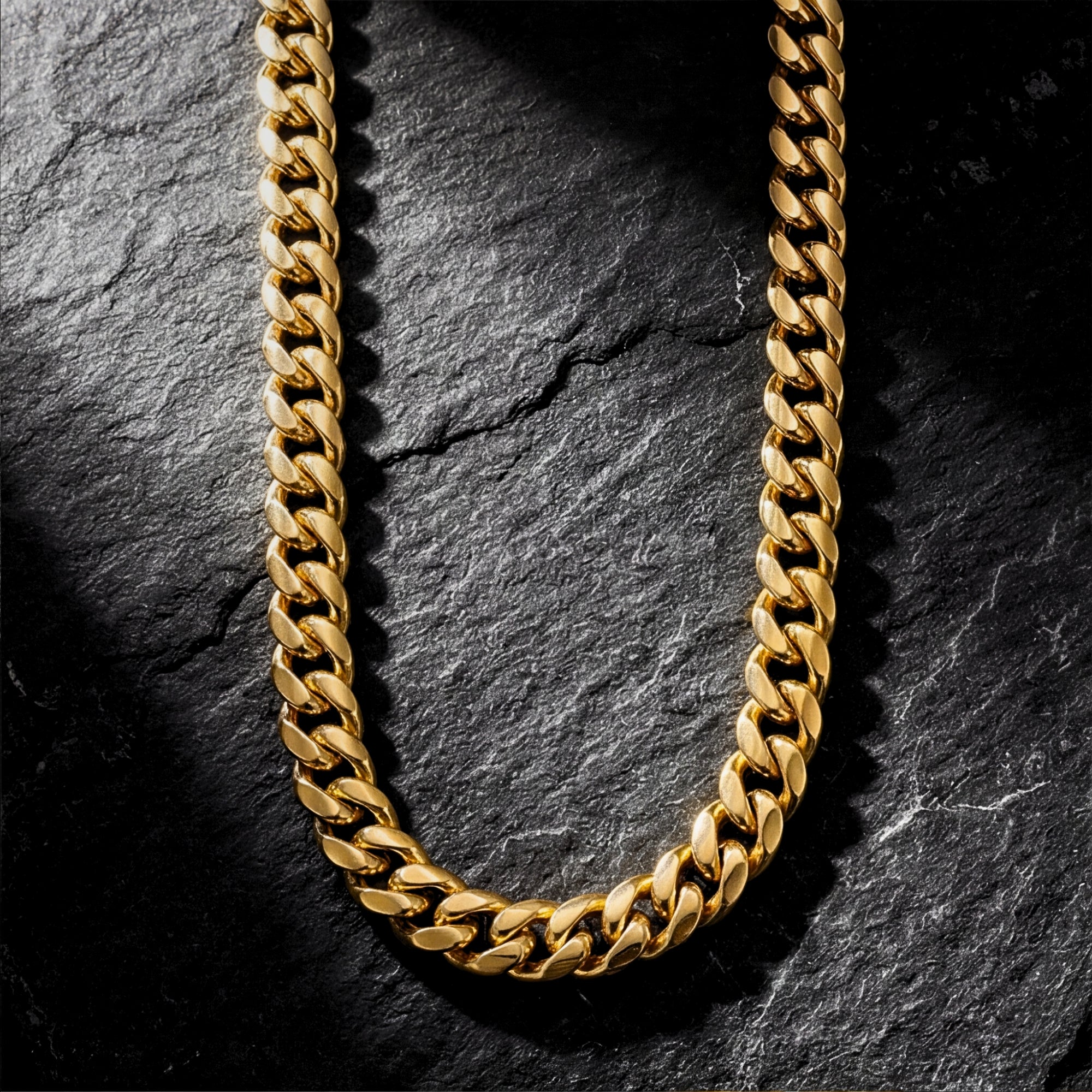 8mm gold ion-bonded stainless steel Cuban link chain necklace laid out on a dark, textured stone surface.