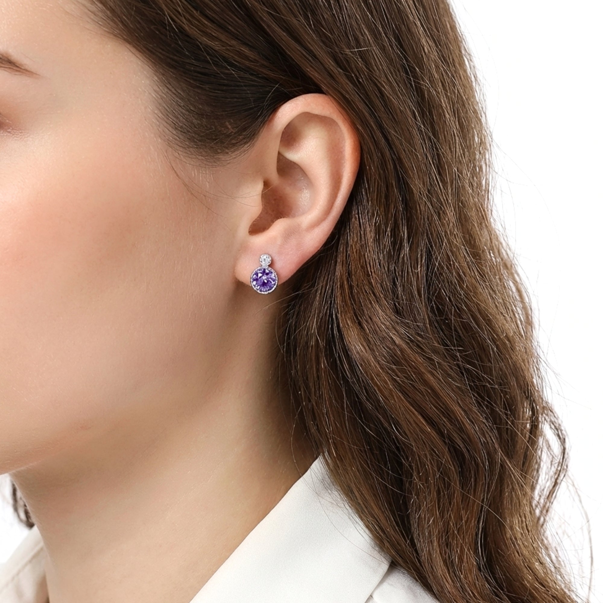 Woman with brown hair wearing a round purple simulated amethyst stud earring in S925 sterling silver.