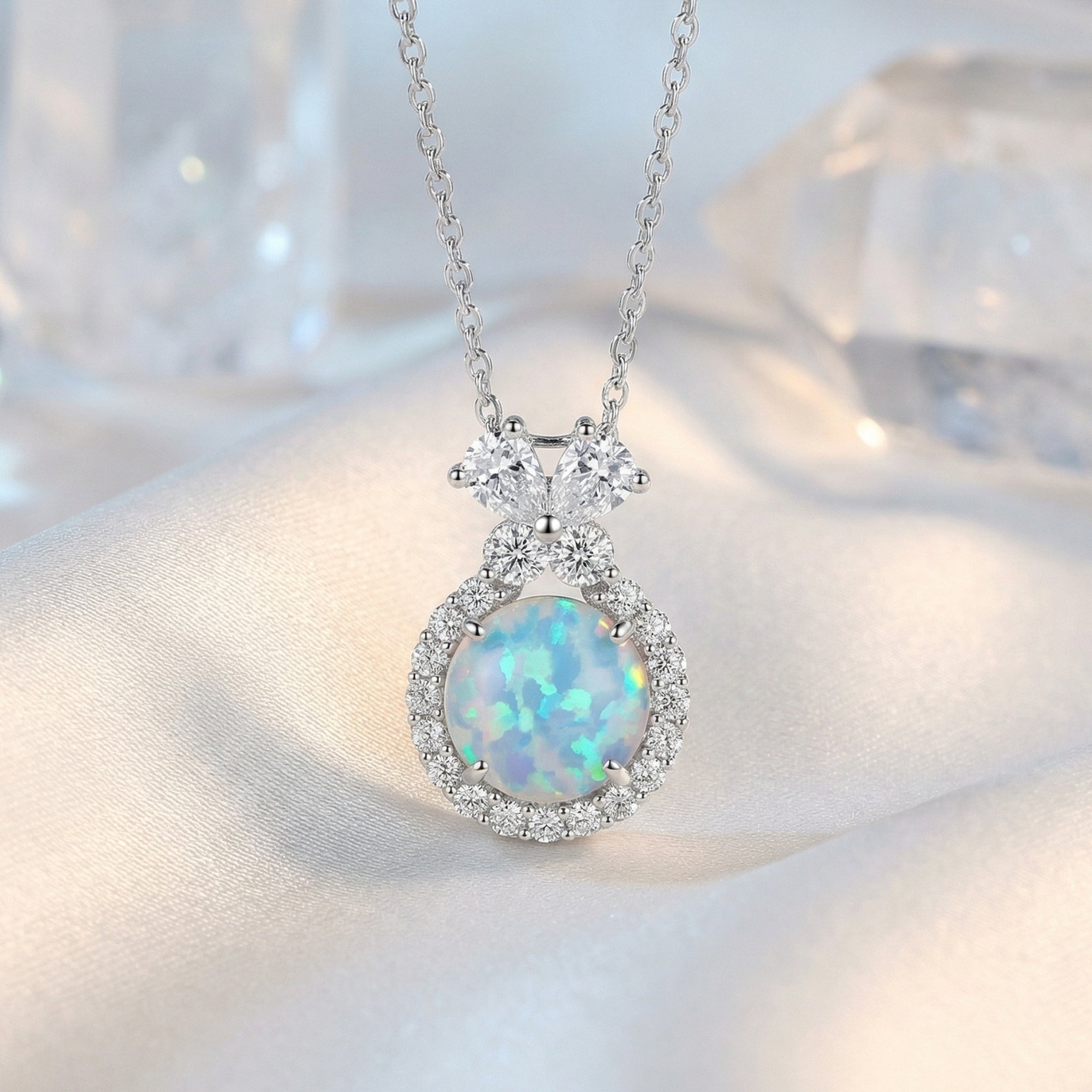 Macro view of the sterling silver necklace showing the round blue opal pendant and intricate crystal halo.