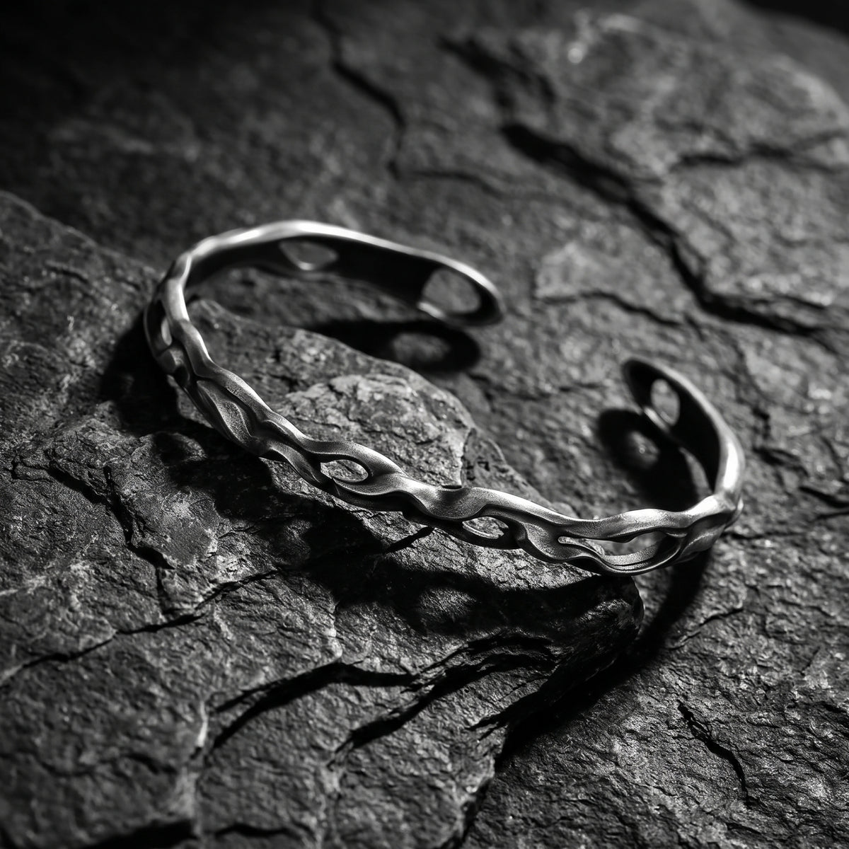 Angled close view of the open silver wave cuff bracelet resting diagonally on dark slate.