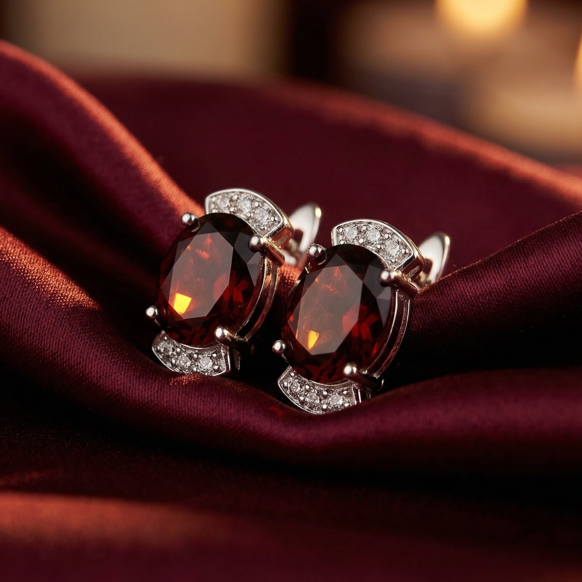 Close-up of oval cut natural garnet drop earrings in sterling silver showing the intricate stone setting and accents.