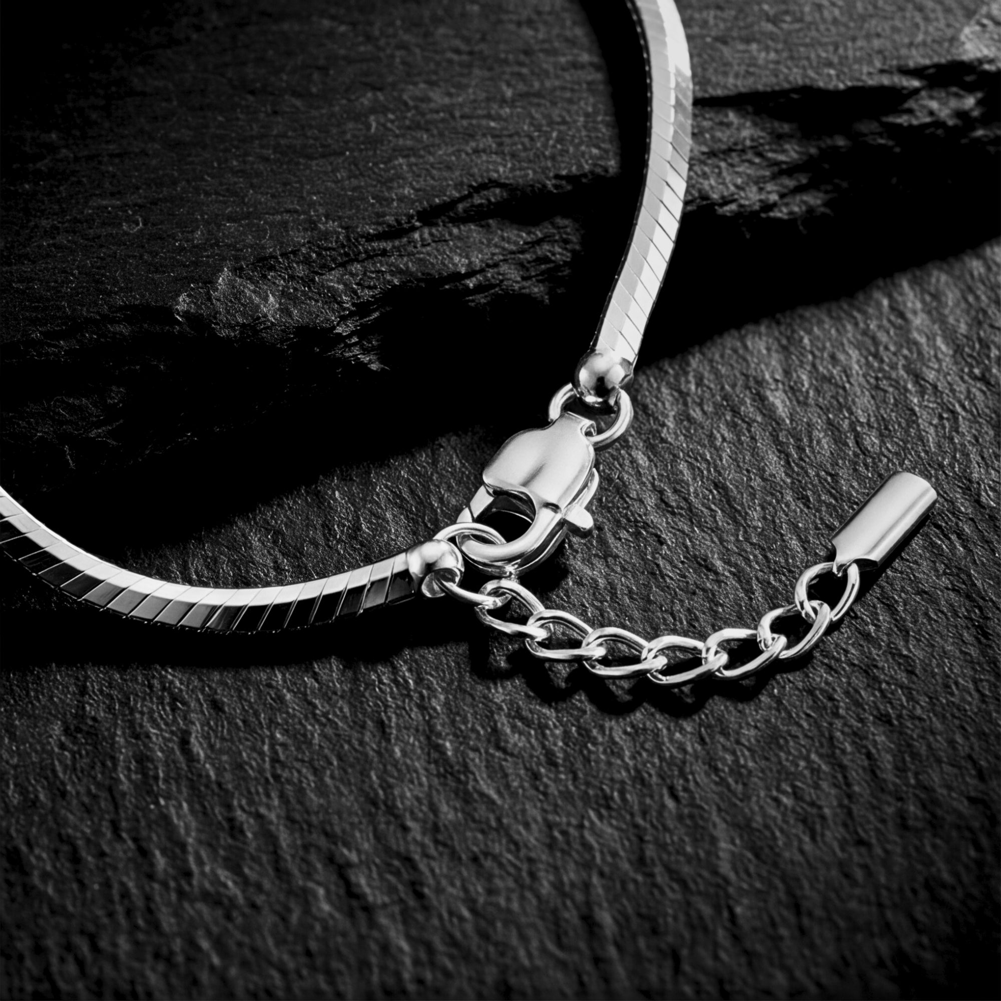 Detail view of the lobster clasp and extender chain on a silver stainless steel octagon link bracelet.