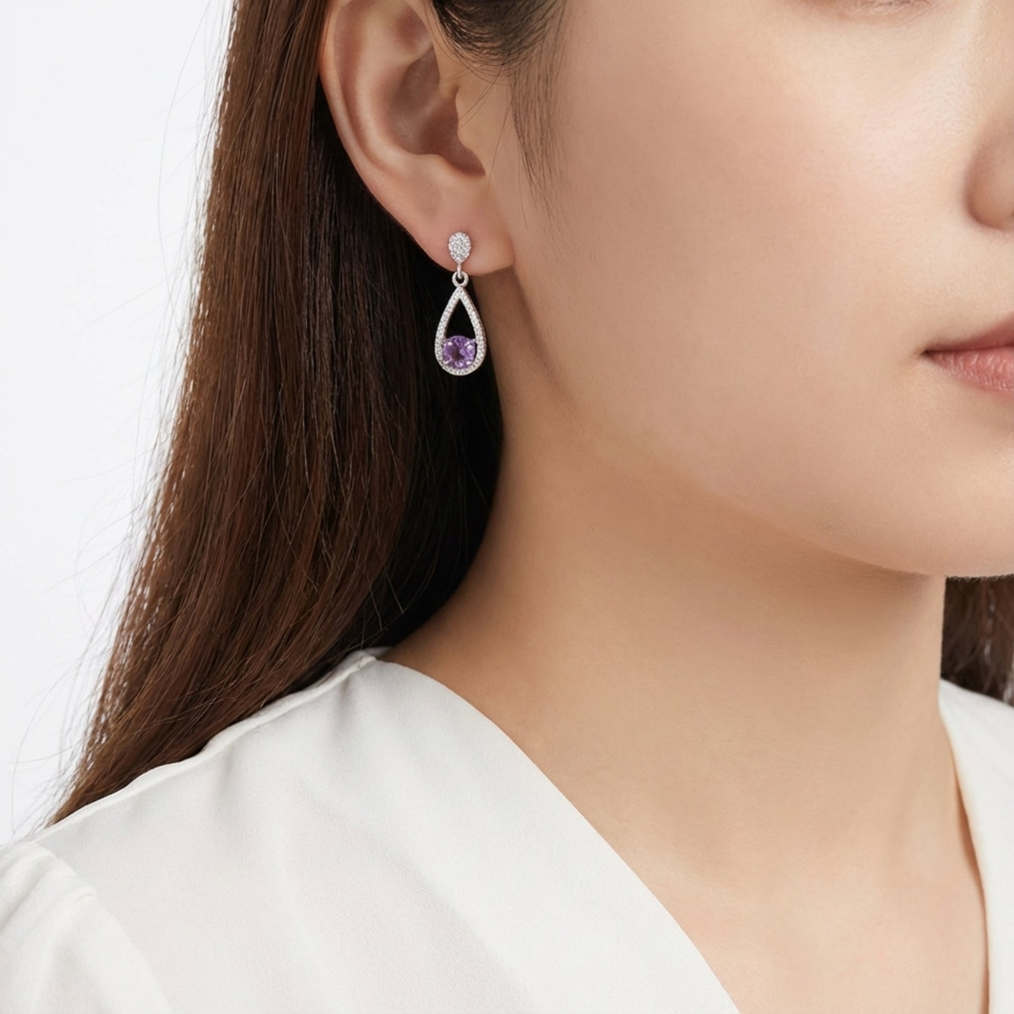 Woman wearing a sterling silver teardrop halo earring with a round-cut simulated amethyst.