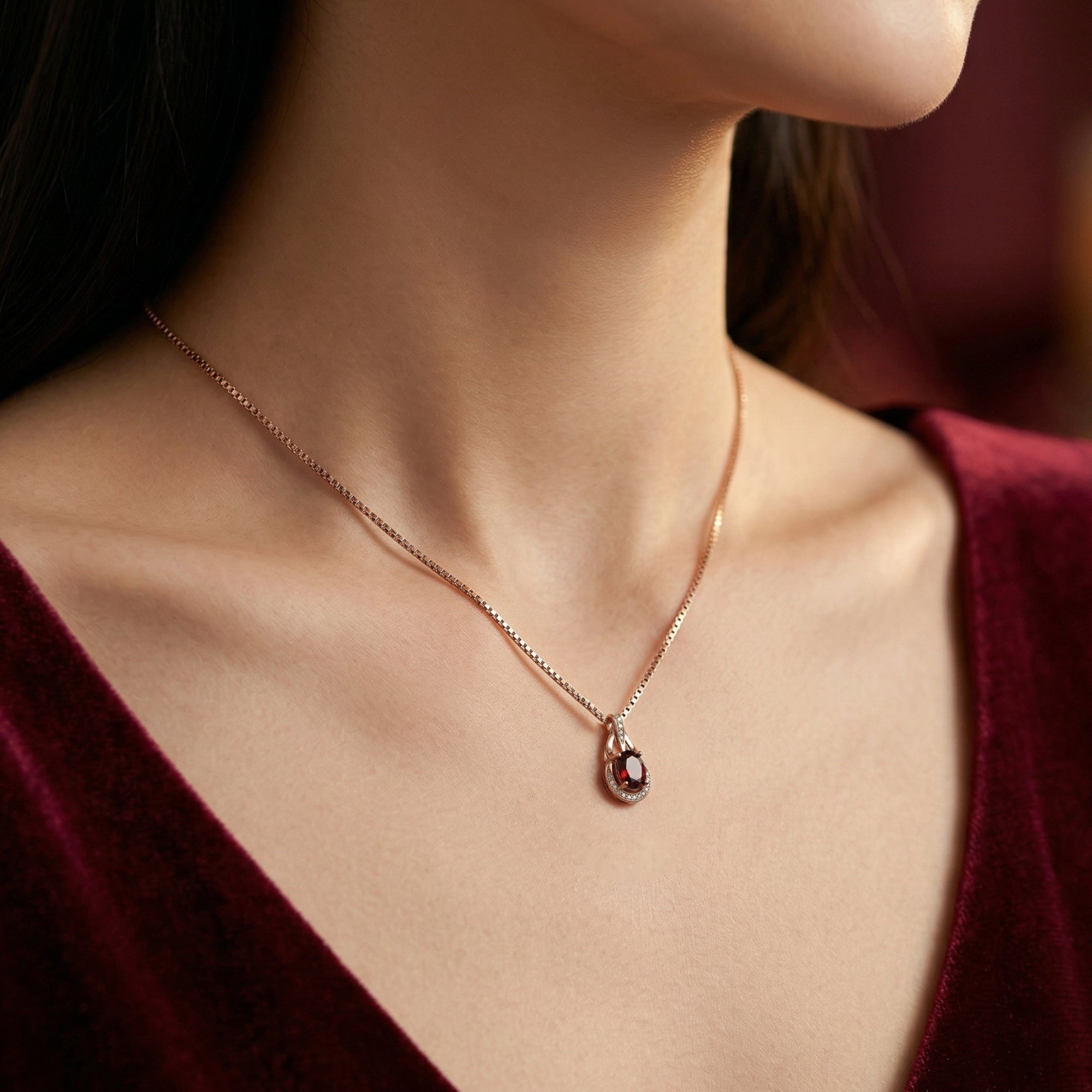 Front view of the Valencia 18K rose gold necklace with an oval garnet pendant on a model.