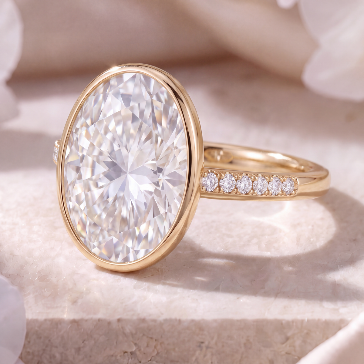 Angled side view of an oval moissanite bezel ring with a pavé band in yellow gold.