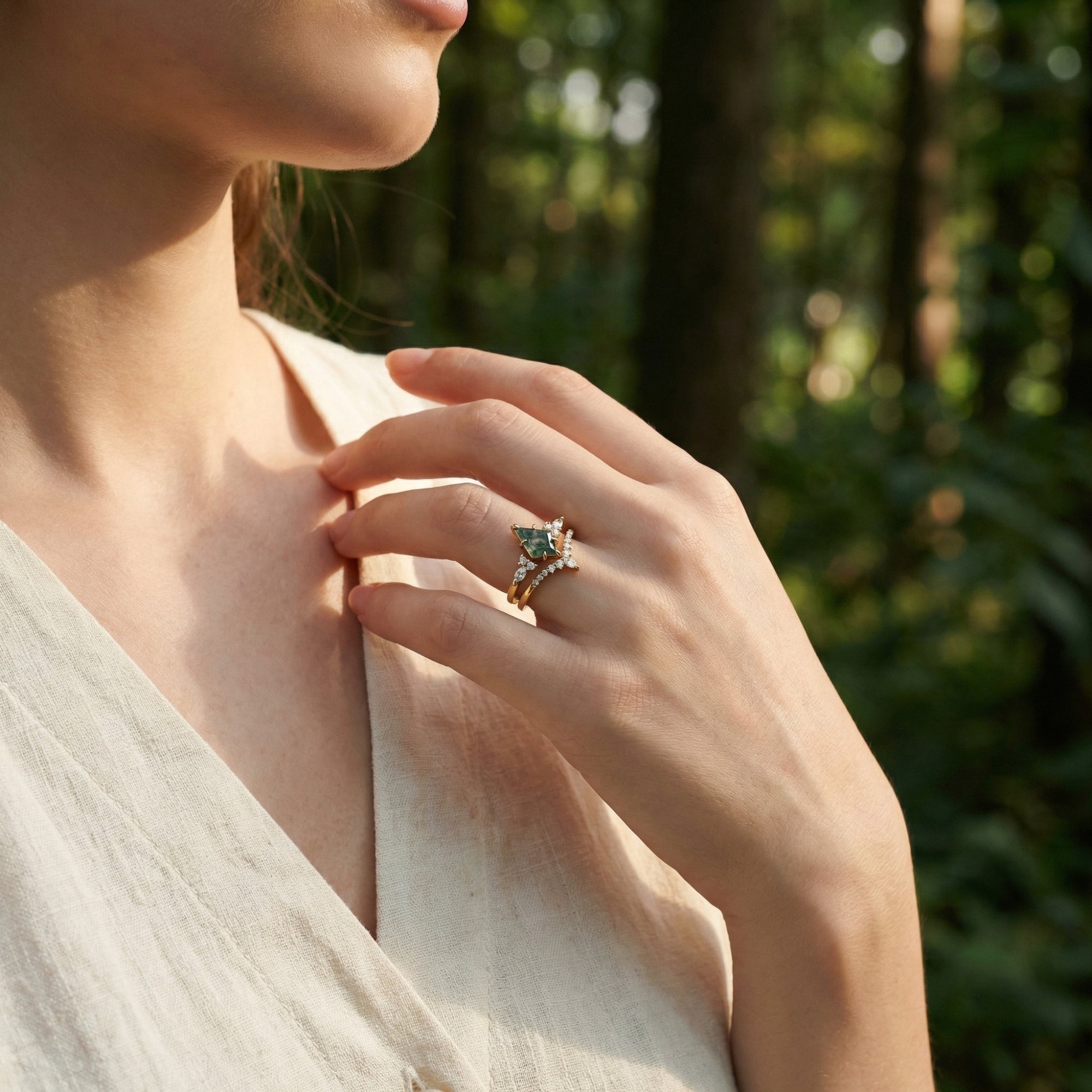 Model wearing the kite-cut moss agate and gold-plated sterling silver duo ring set against a forest backdrop.