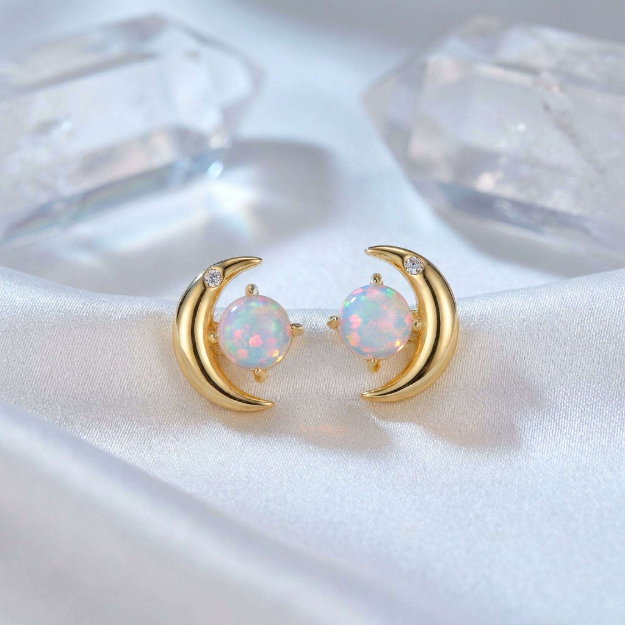 Detailed view of gold-tone crescent moon stud earrings with round cabochon opal stones and small clear accents.