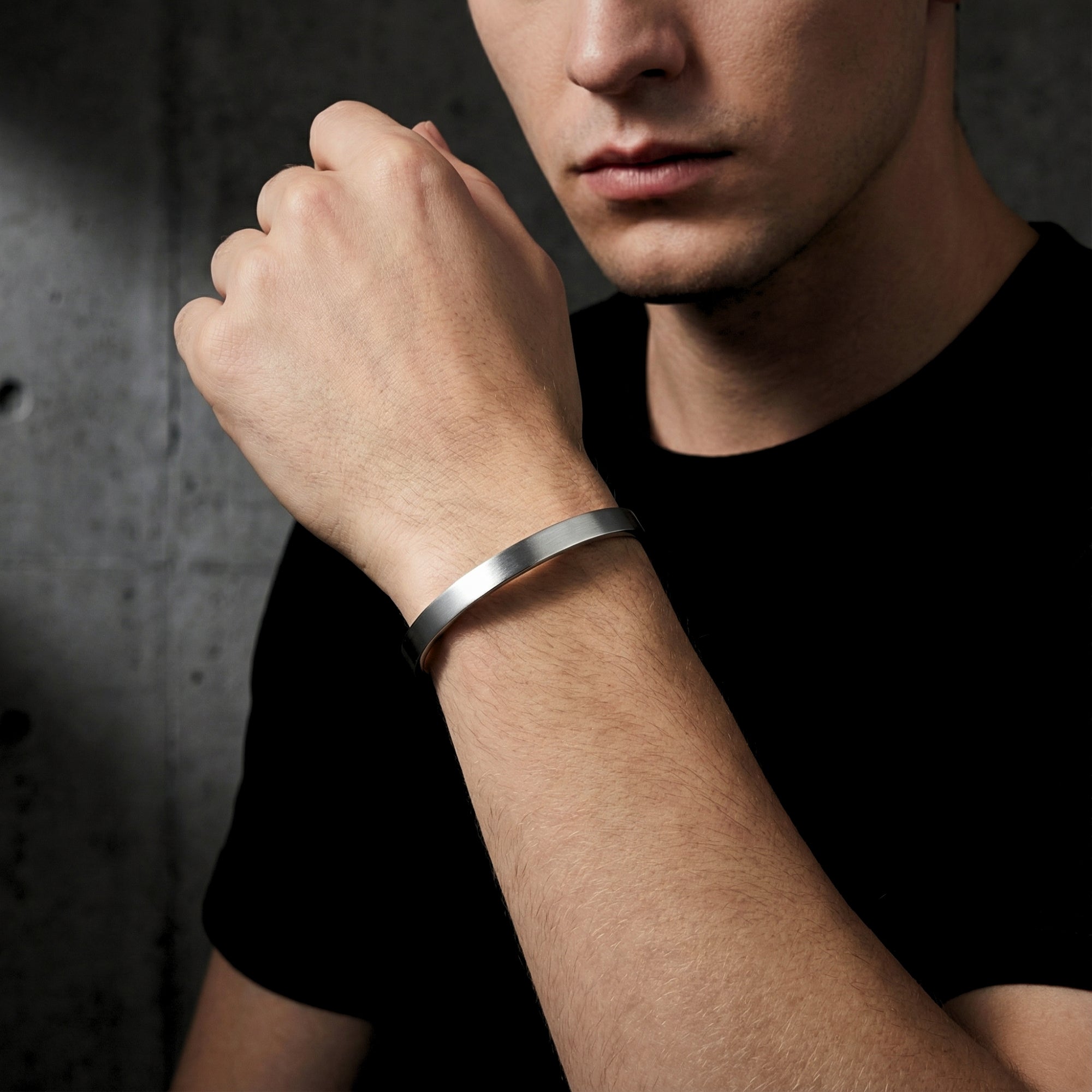 Men's brushed silver stainless steel cuff bracelet worn on a wrist.