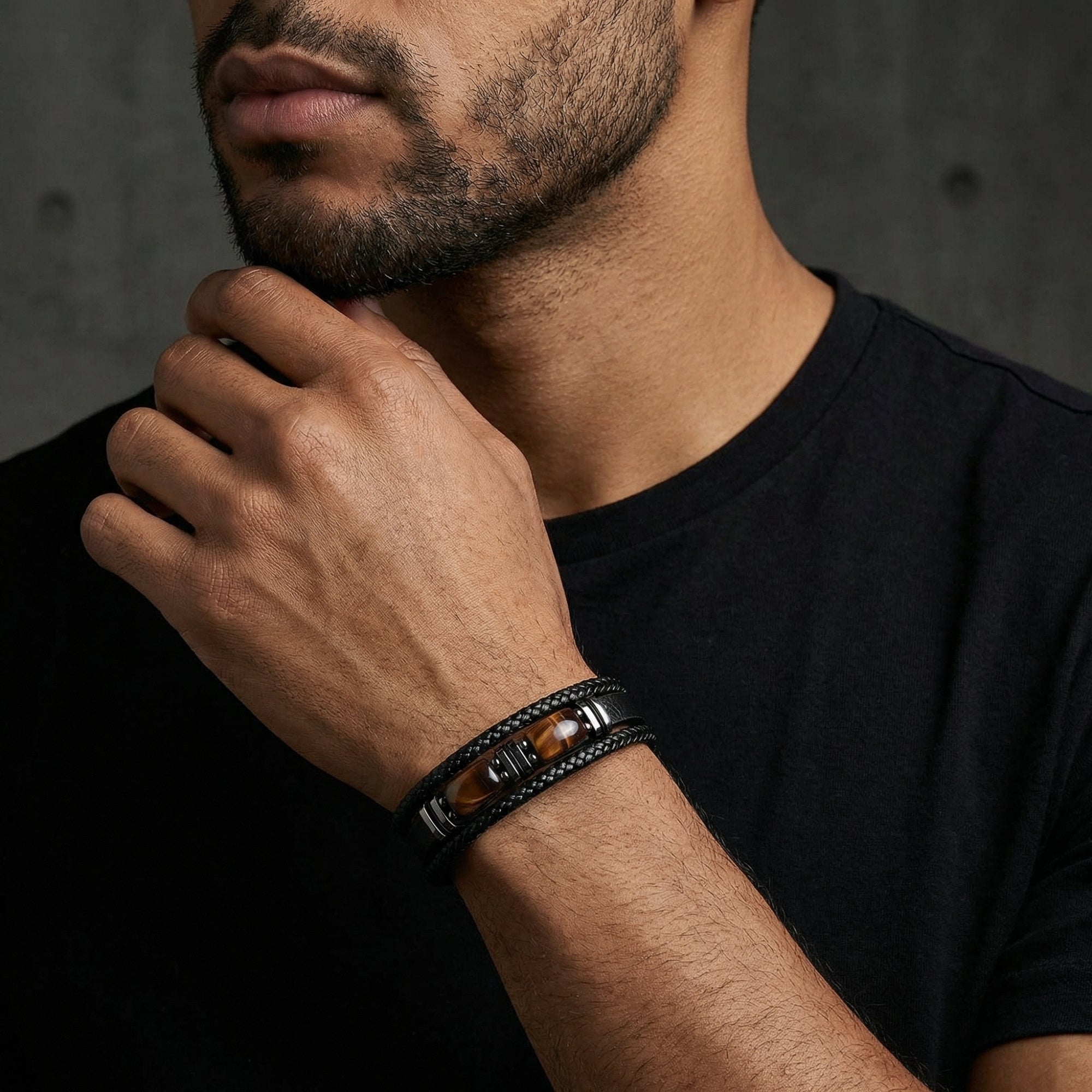 Men's black braided leather bracelet with red-toned accents and black steel hardware worn on a model's wrist.