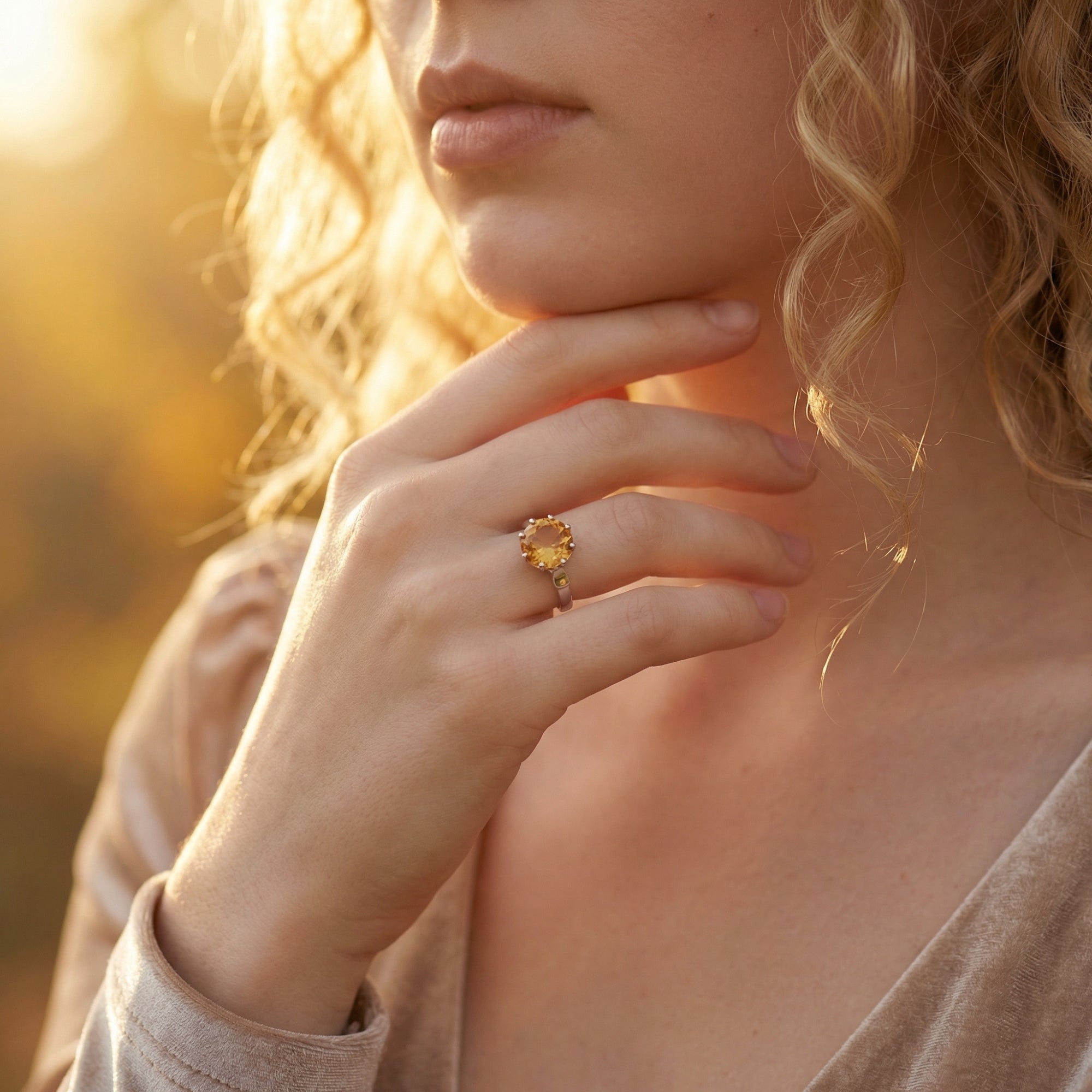 A woman wearing the sterling silver round cut natural citrine ring, styled with a velvet dress in warm light.