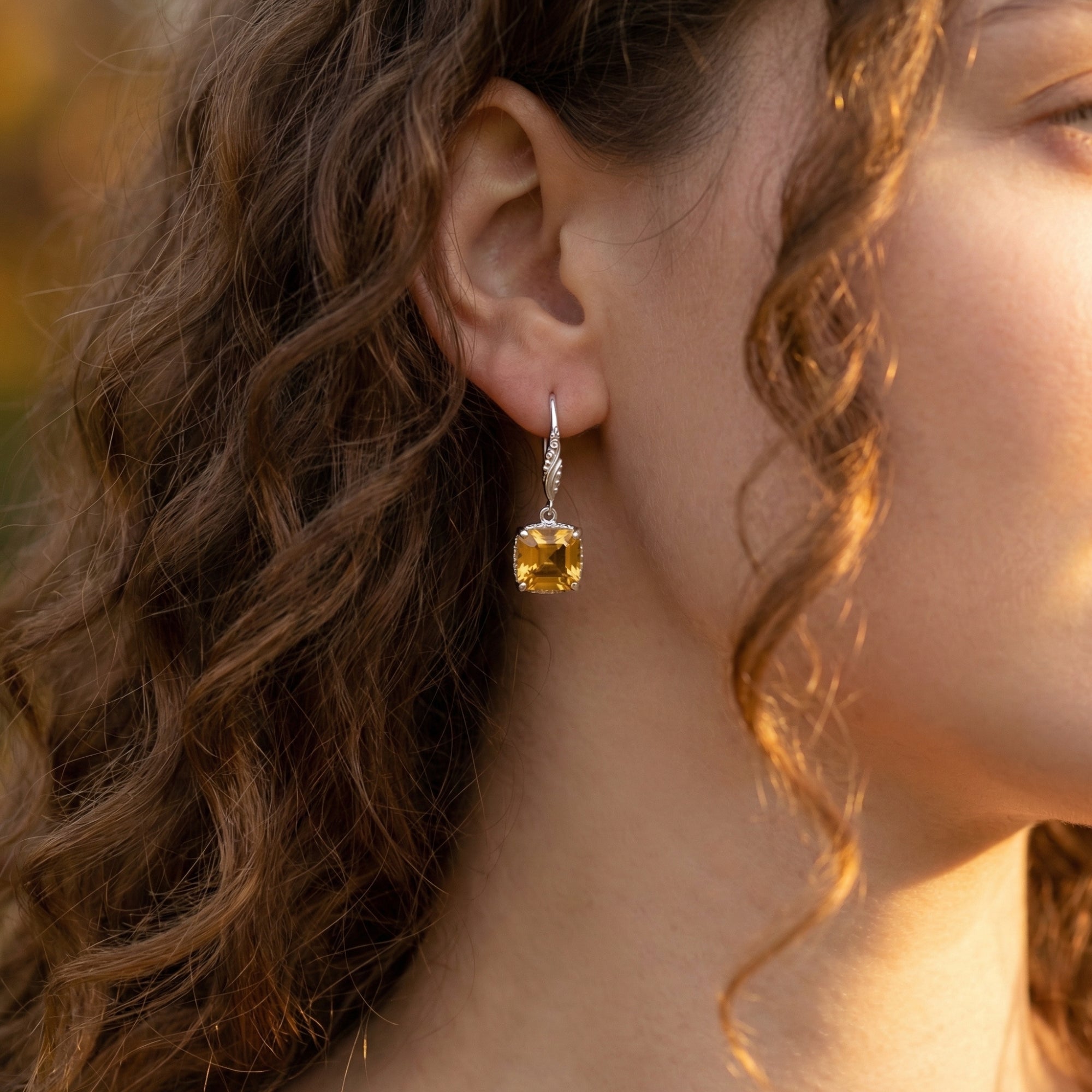 Side view of a woman wearing a silver square cut natural citrine drop earring from the Solis collection.