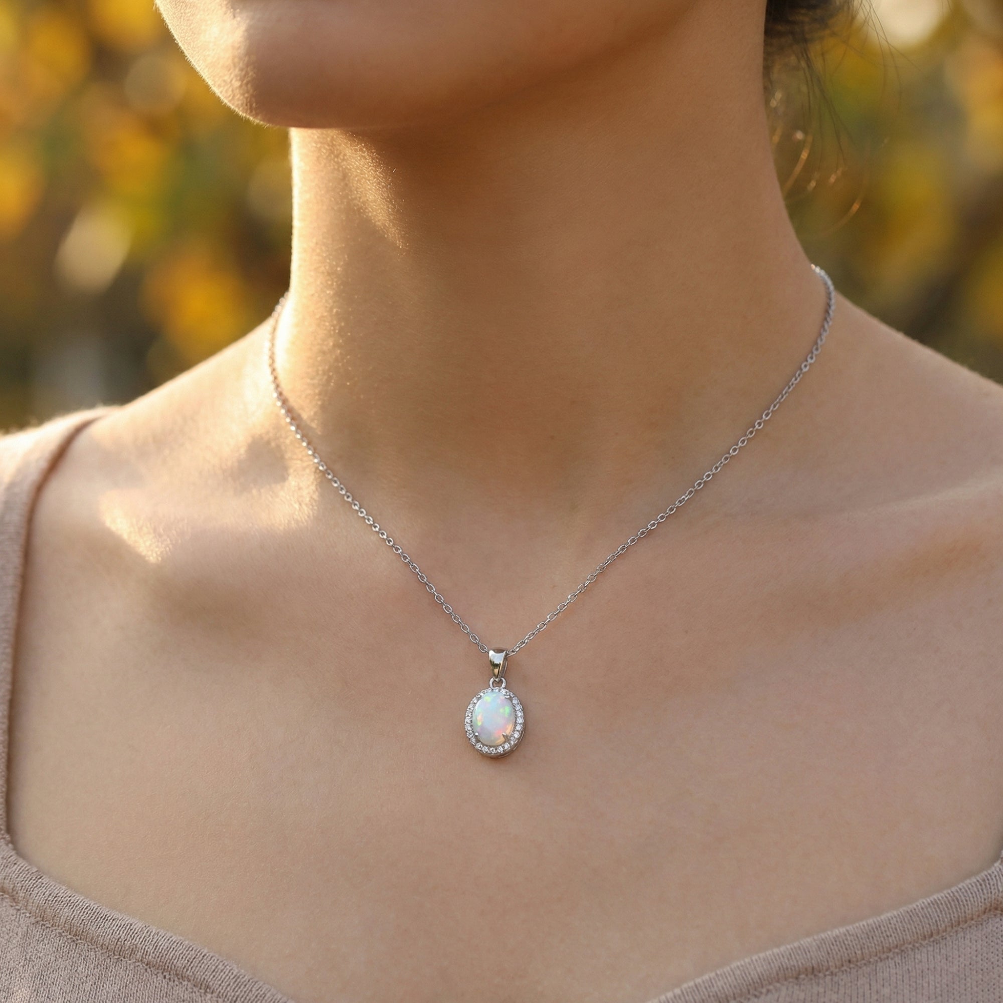Minimalist S925 sterling silver necklace with an oval cut white opal pendant worn by a model.